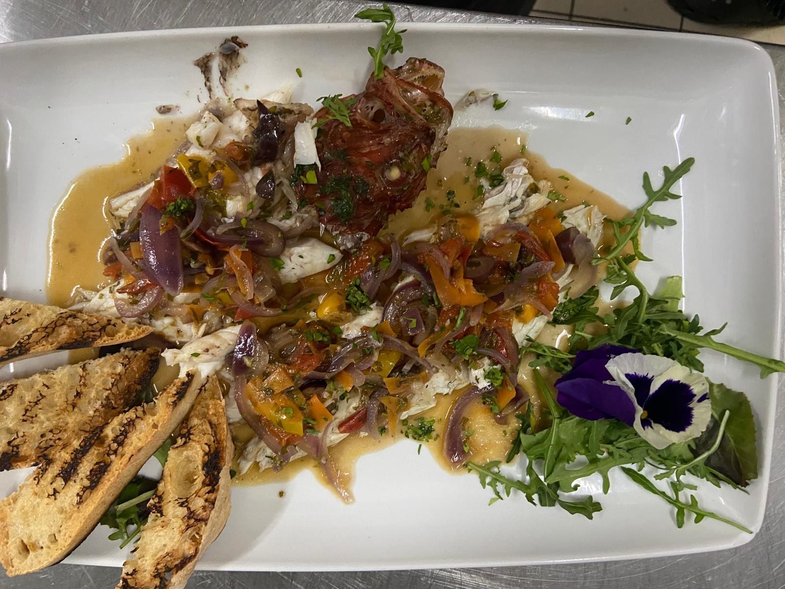 Un piatto bianco sormontato da una varietà di verdure e pane