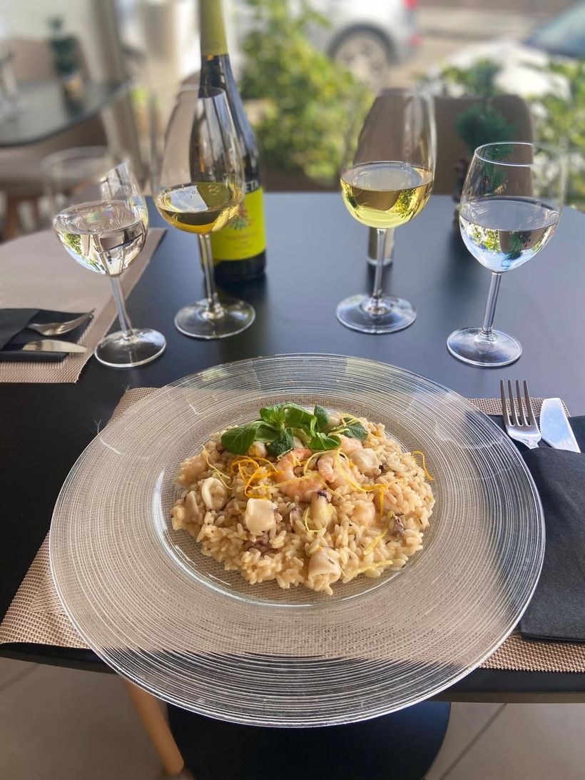 Un piatto di cibo e bicchieri di vino su un tavolo.