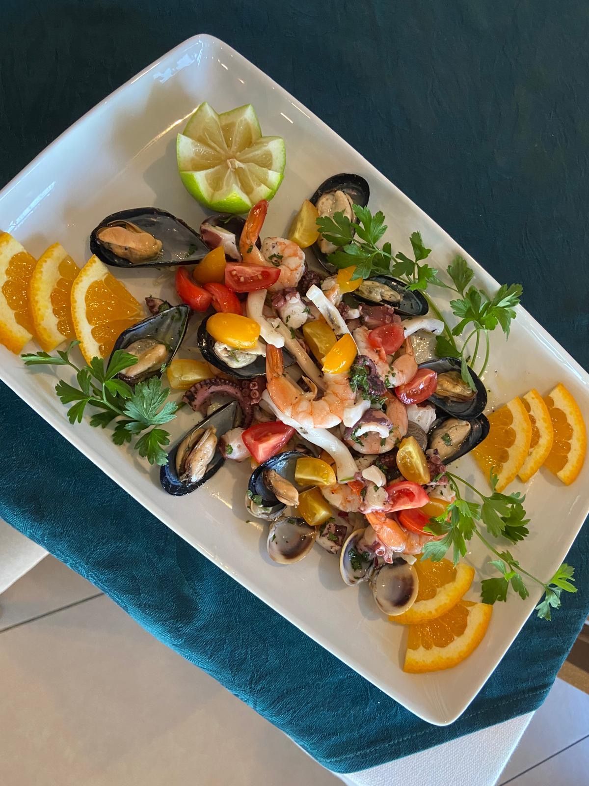 Un piatto bianco guarnito con frutti di mare e fette d'arancia