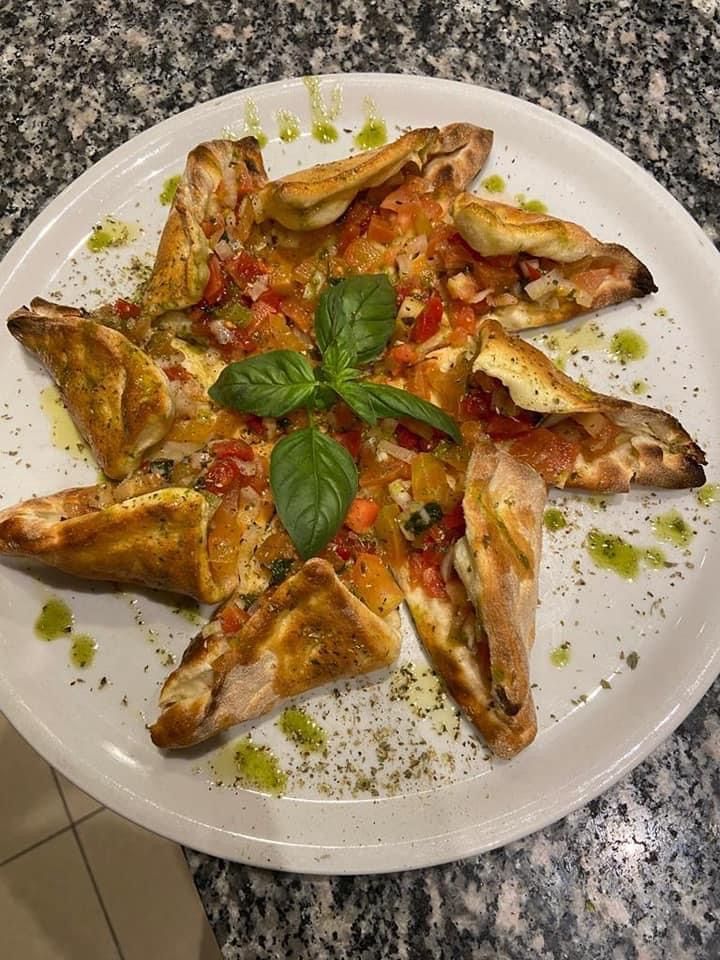 Un piatto bianco sormontato da una pizza a forma di stella.