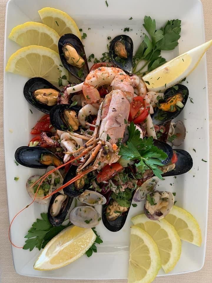 Un piatto bianco guarnito con frutti di mare e fette di limone.