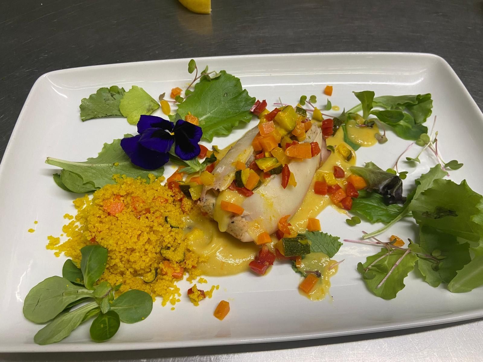 Un piatto di cibo con verdure e fiori sopra