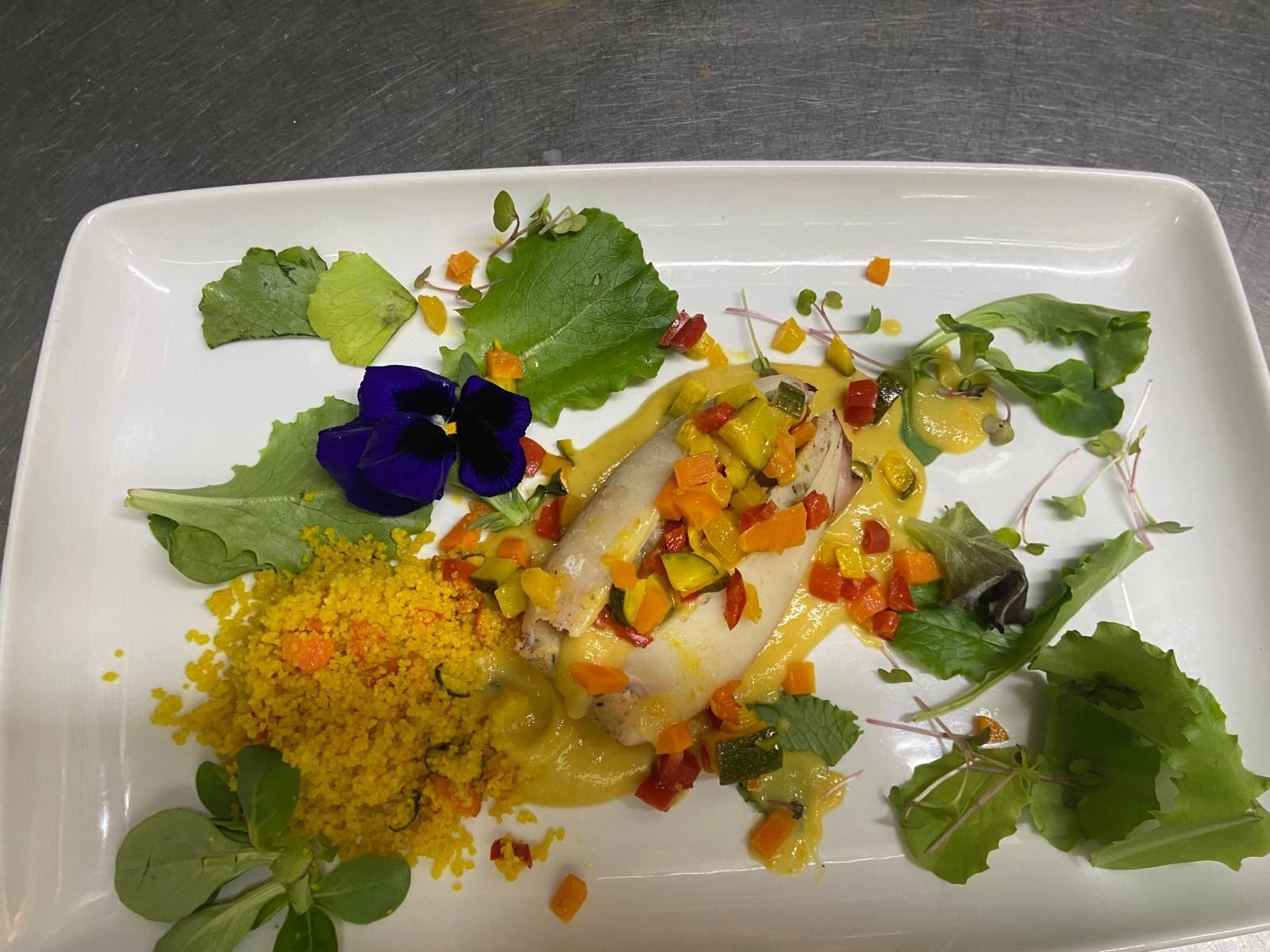 Un piatto di cibo con verdure e fiori sopra