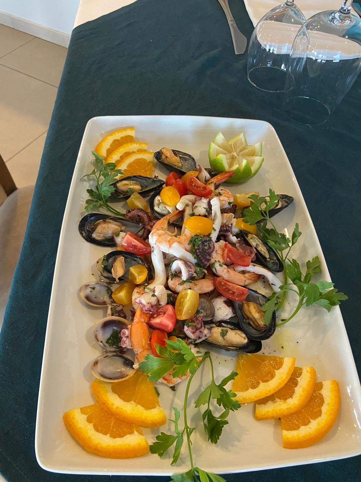 Un piatto bianco con frutti di mare e arance su un tavolo