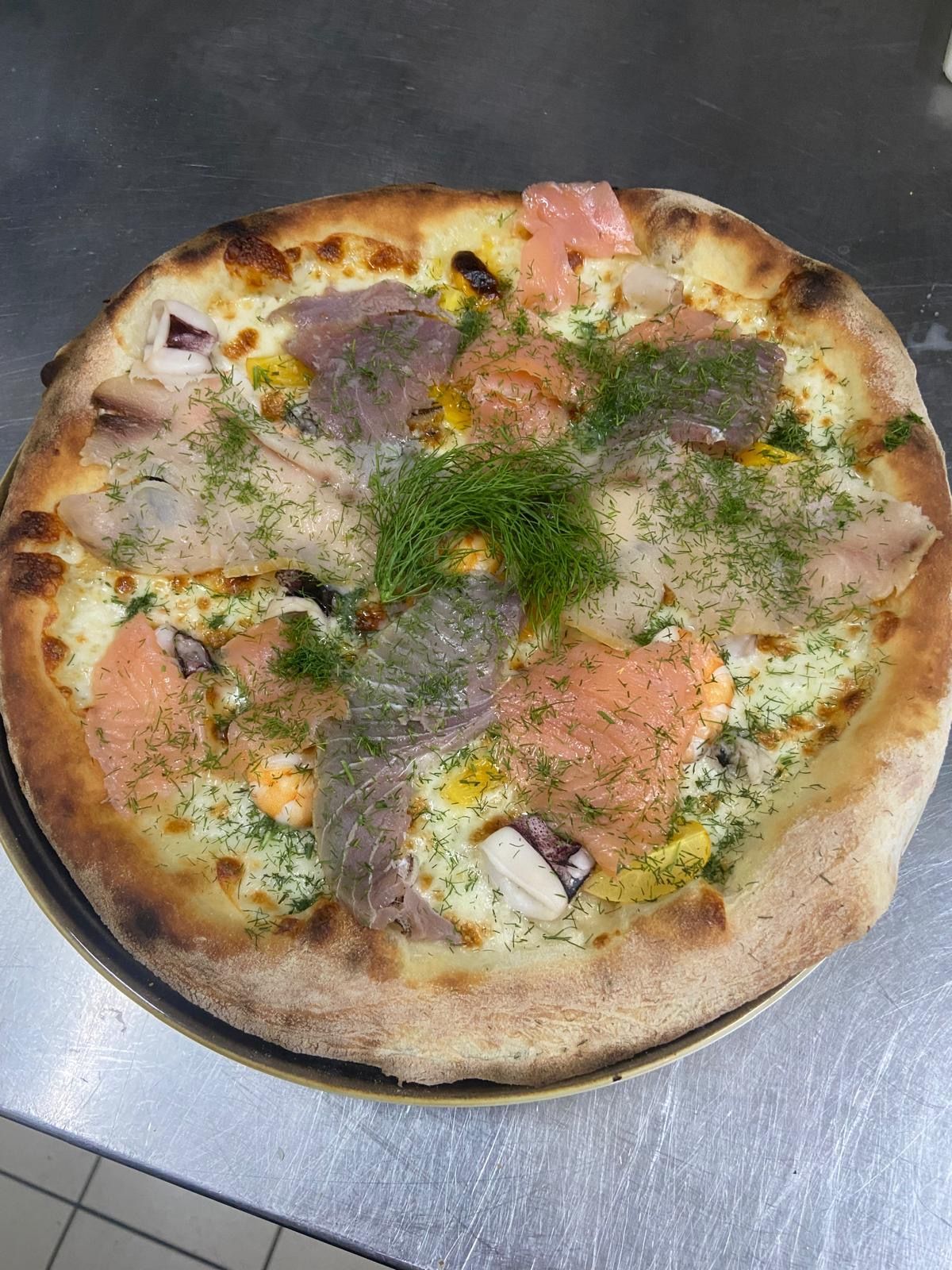 Una pizza con tanti condimenti è su un piatto su un tavolo.
