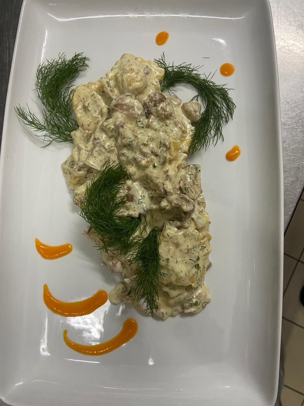 Un piatto bianco condito con salsa e aneto su un tavolo.