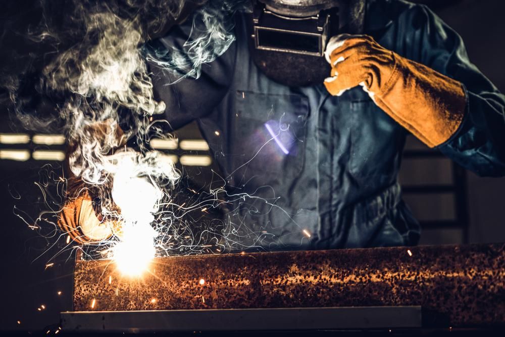 A Man Is Welding a Piece of Metal in A Factory — K & S Sheetmetal in Gladstone Central, QLD