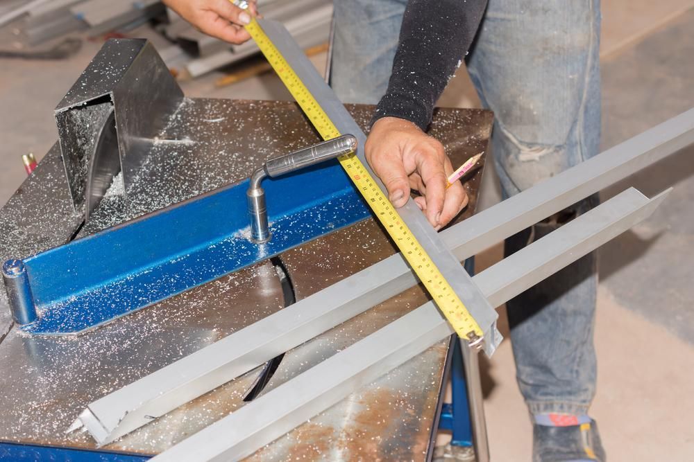 A Man Is Measuring a Piece of Metal with A Tape Measure — K & S Sheetmetal in Biloela, QLD
