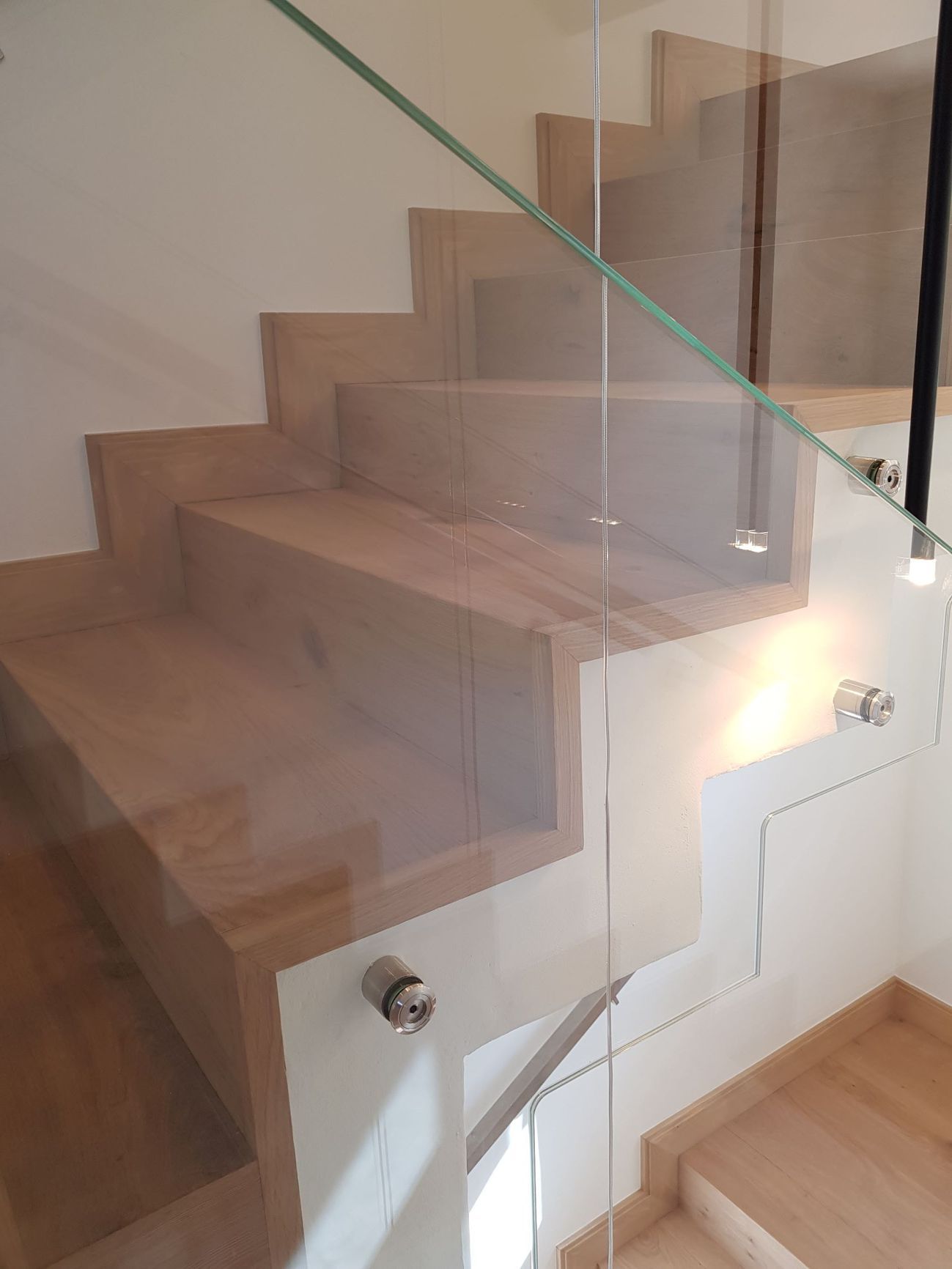 Escalier en bois avec rampe en verre. Intérieur moderne et lumineux.