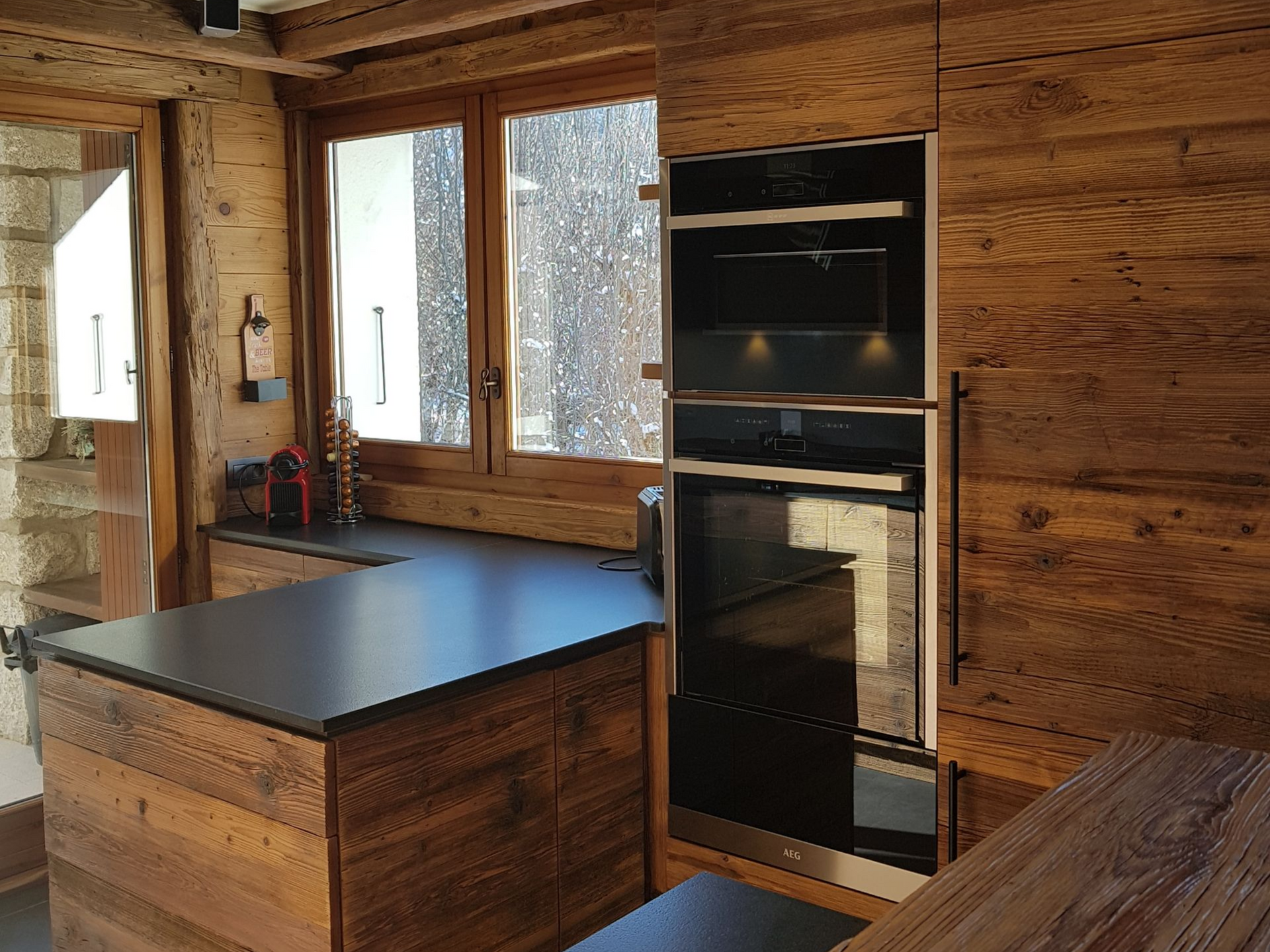 Cuisine en bois avec îlot central et comptoir noir, et appareils électroménagers intégrés.