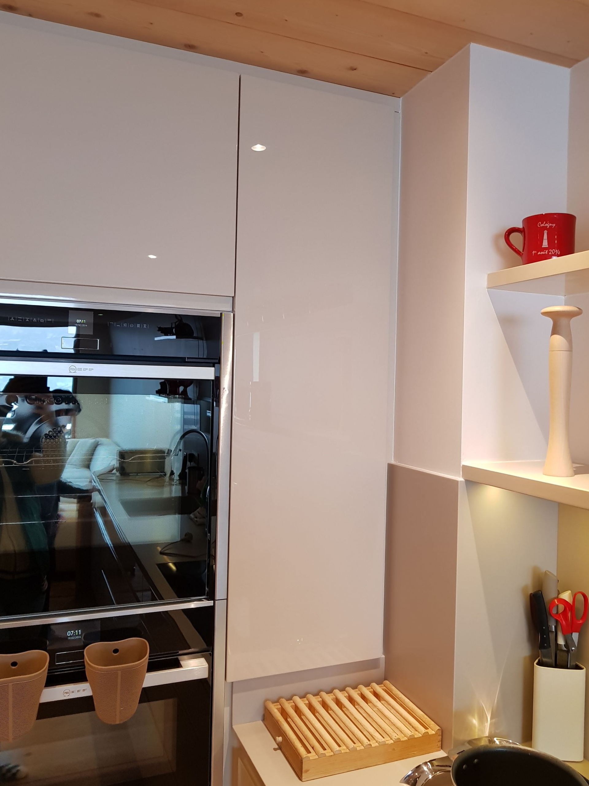 Cuisine équipée de placards blancs, d'un four et d'étagères intégrées. Comprend une planche à pain en bois.