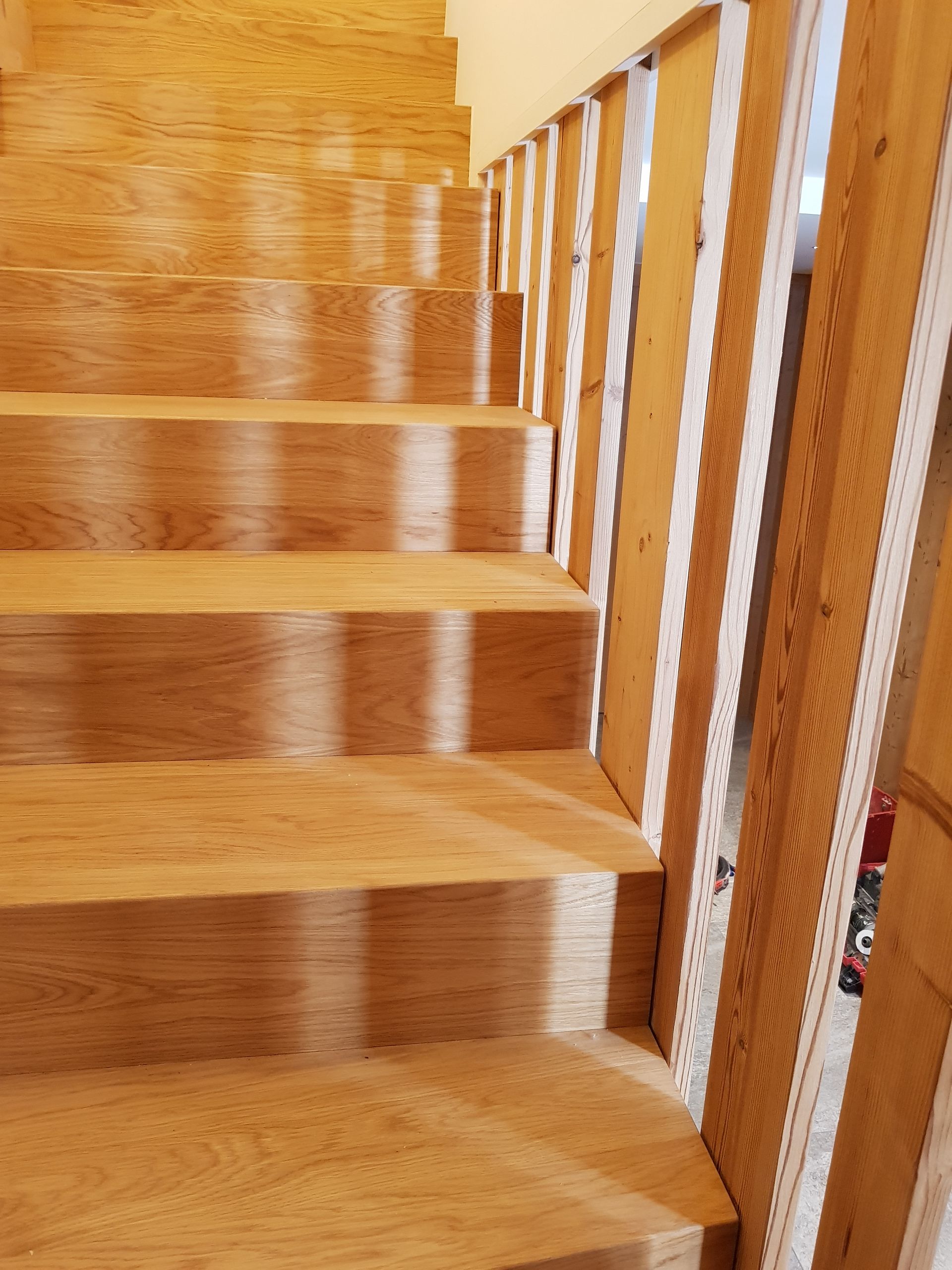 Escalier en bois avec jeux d'ombre et de lumière, et rampe blanche et en bois.