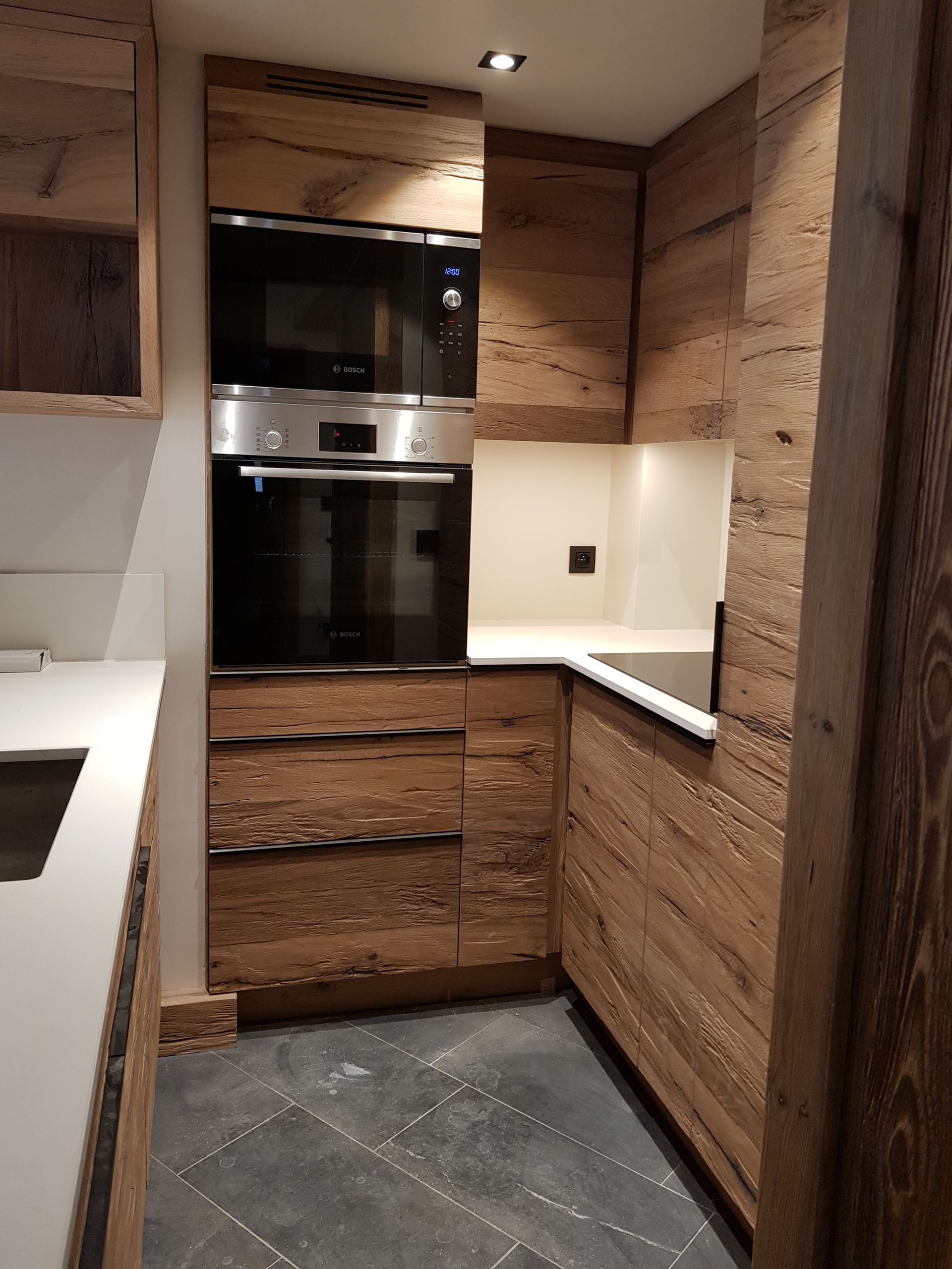 Îlot de cuisine en bois avec évier et robinet, placards intégrés et four.