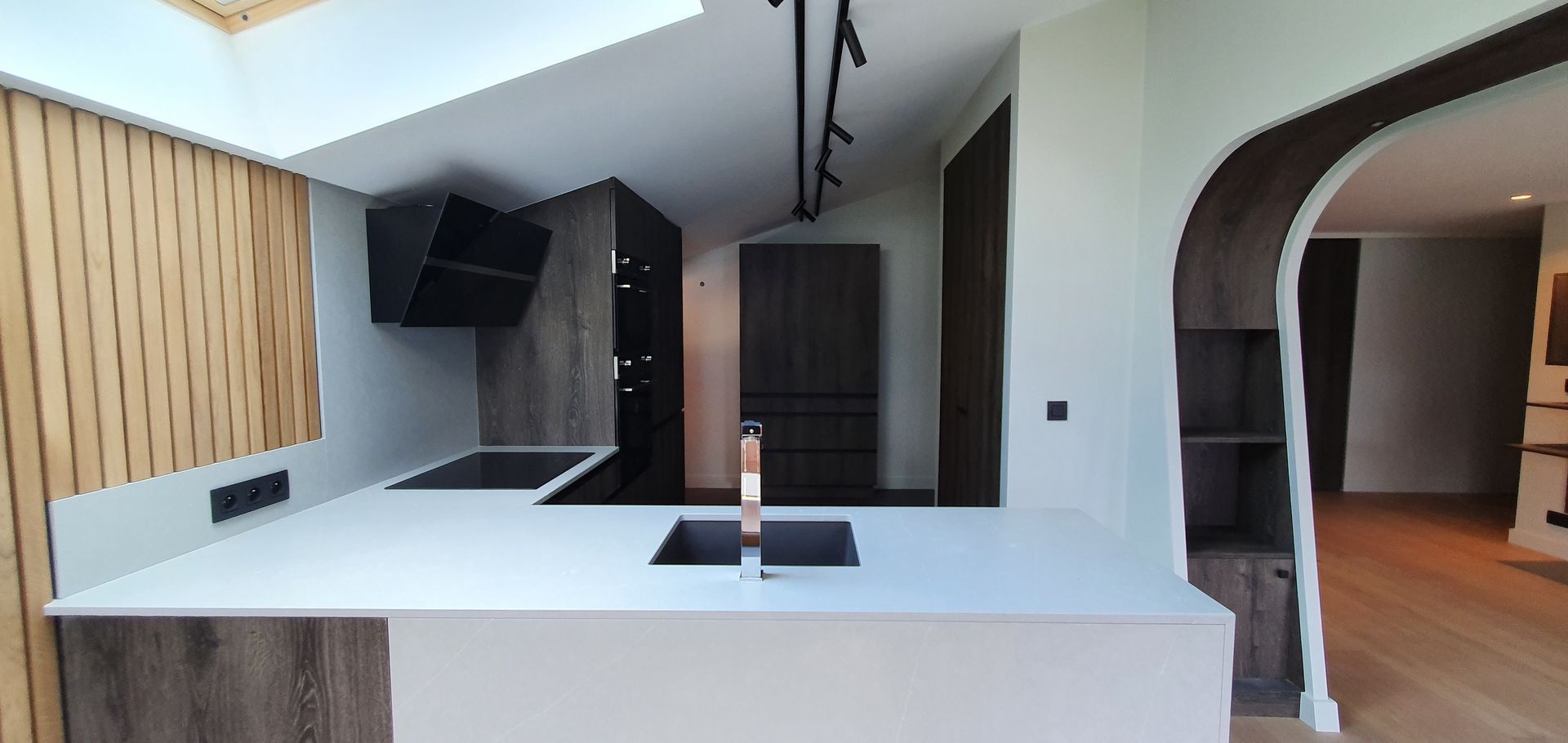 Cuisine moderne avec plan de travail blanc, placards foncés et boiseries.