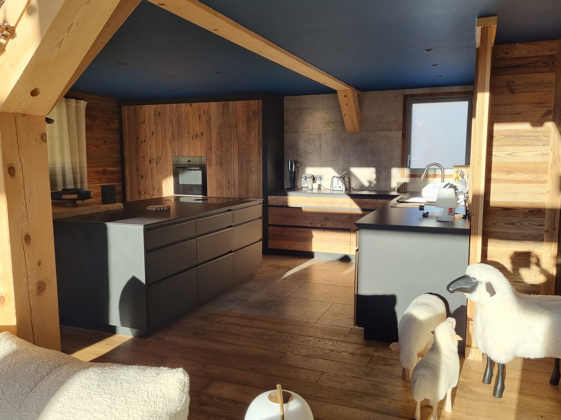 Cuisine de chalet en bois avec comptoirs foncés, boiseries et deux moutons décoratifs.