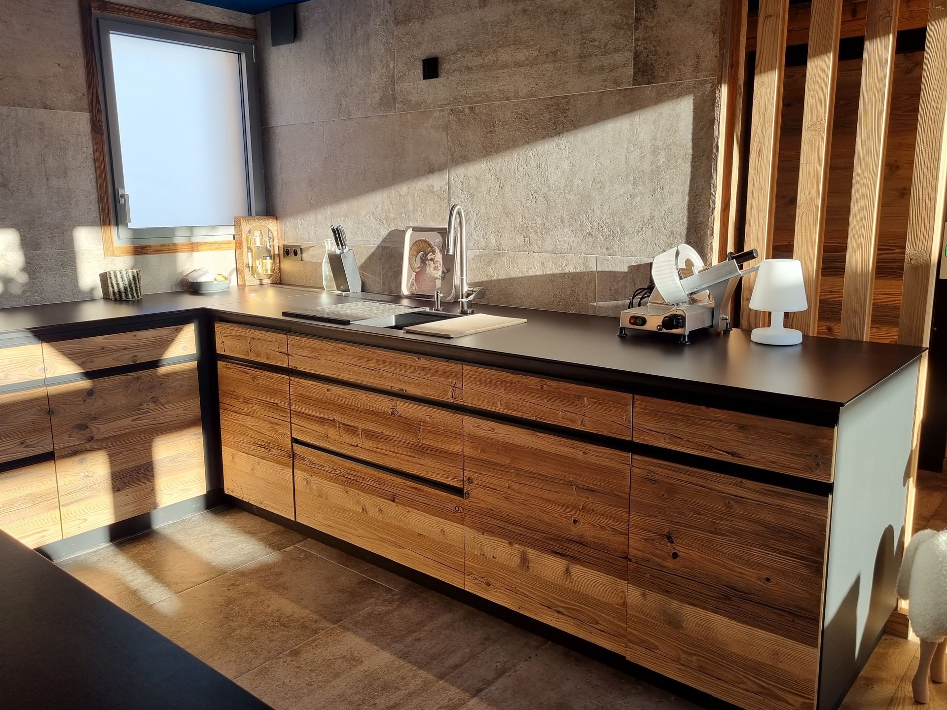 Armoires de cuisine en bois avec comptoirs noirs; une fenêtre et des objets décoratifs sont visibles.