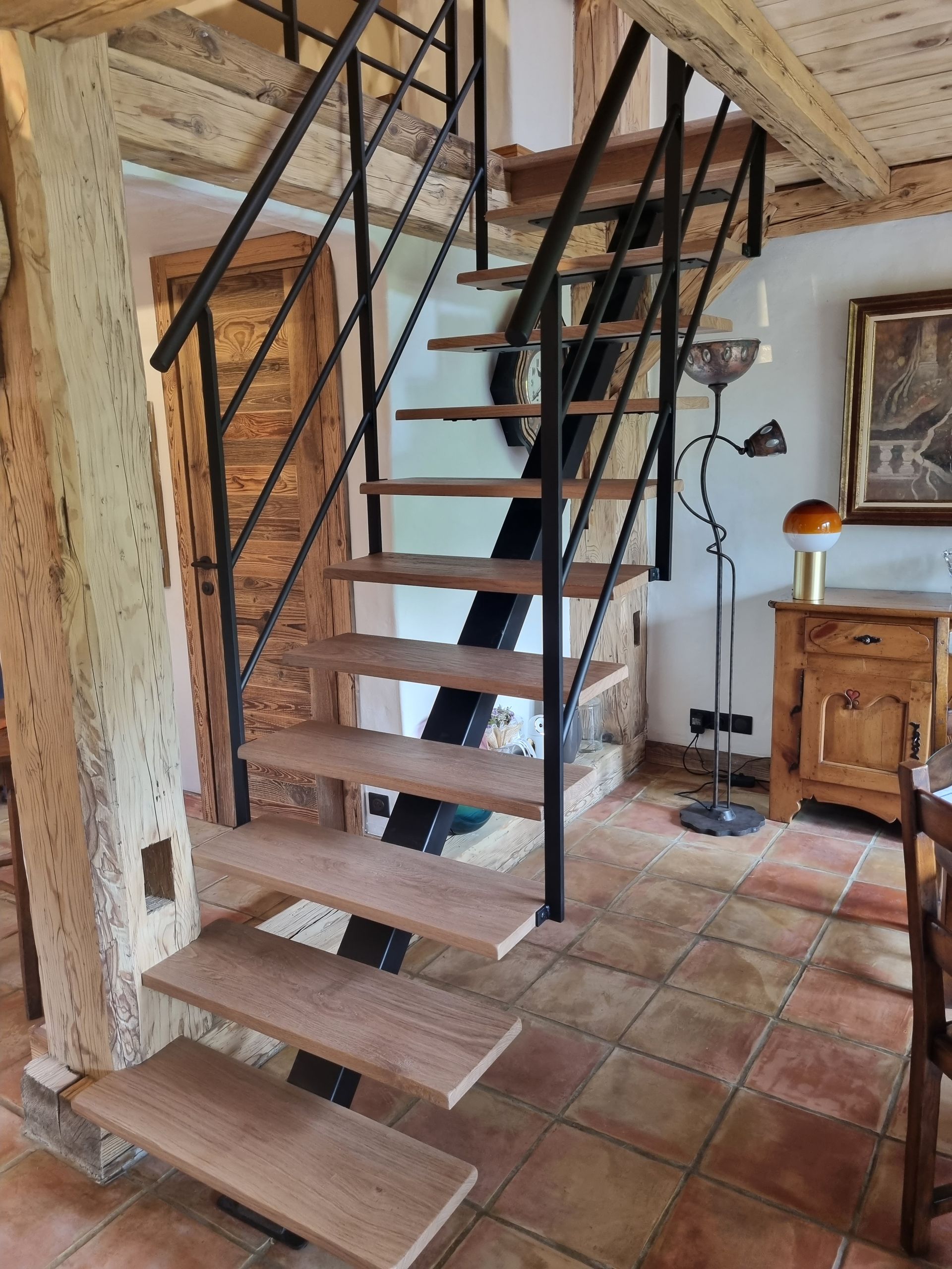 Escalier en bois avec rampe en métal noir dans un intérieur rustique.