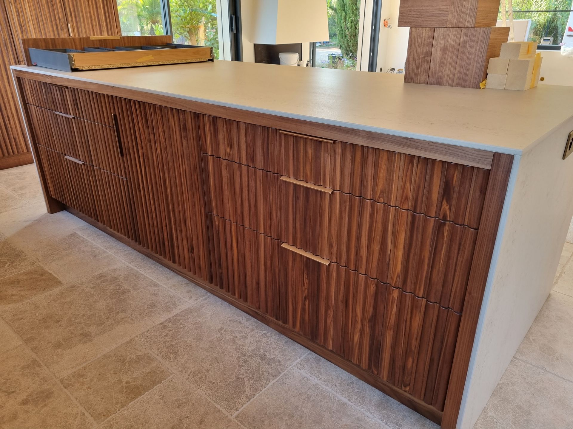 Îlot de cuisine en bois avec façades de tiroirs texturées et plan de travail clair.