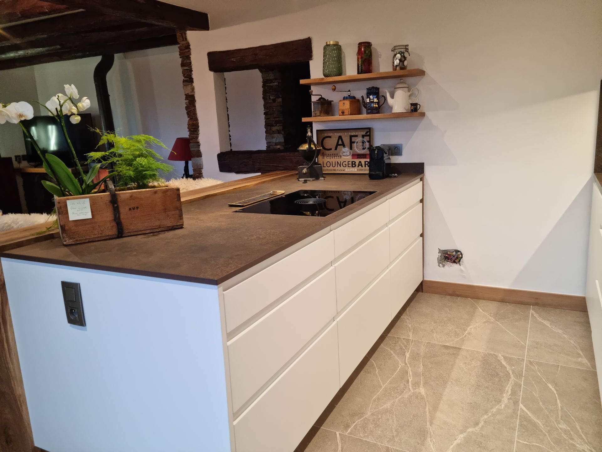 Cuisine moderne avec placards blancs, plan de travail foncé, étagères et sol carrelé gris.