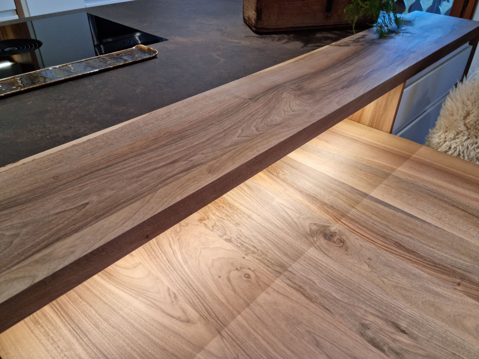 Plan de travail en bois avec plaque de cuisson intégrée et éclairage chaleureux sous le plan de travail.