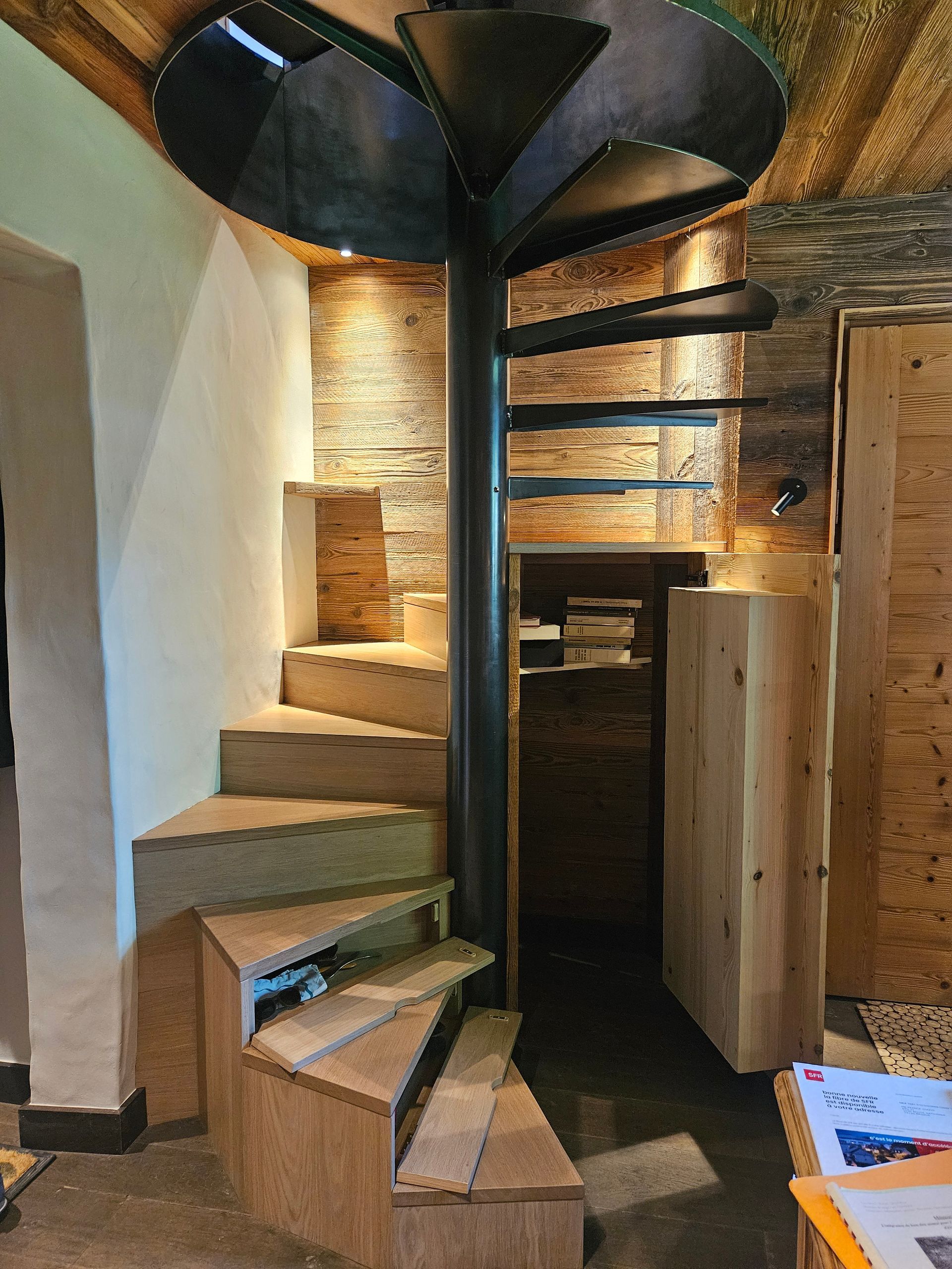 Escalier en colimaçon avec marches en bois et rampe en métal ; vue intérieure.