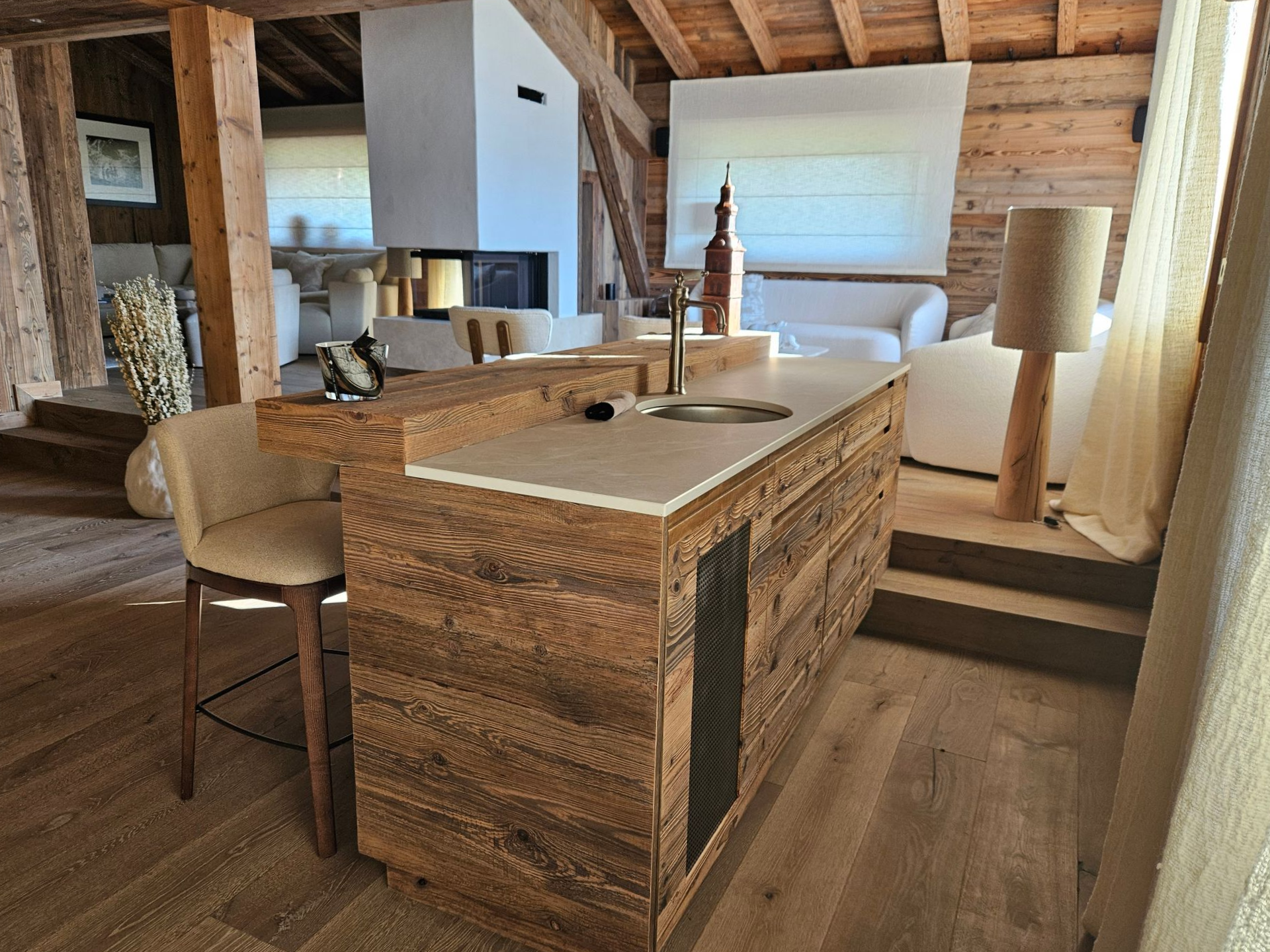 Îlot de cuisine rustique avec évier et bar dans un espace lumineux avec poutres en bois.