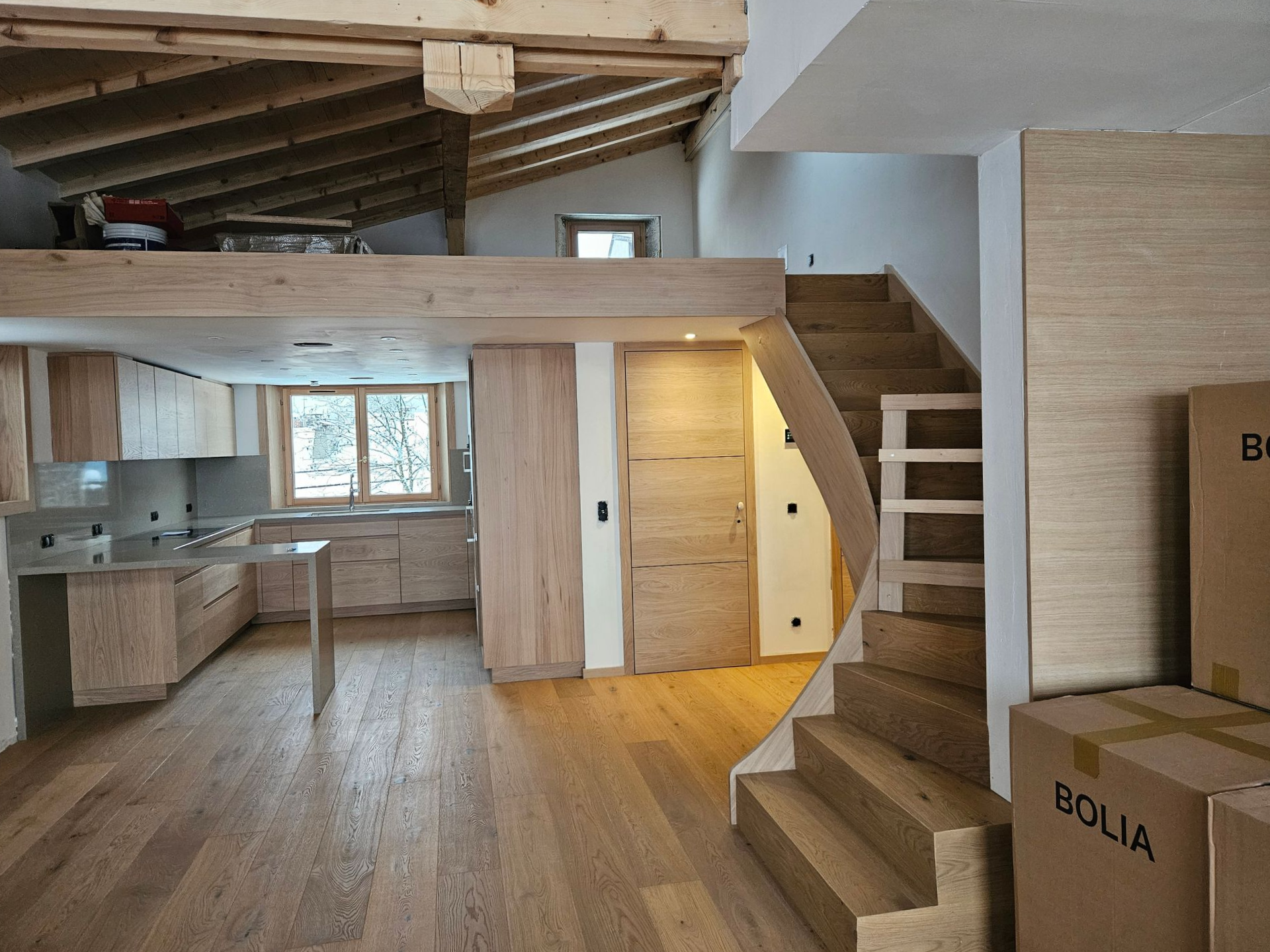 Intérieur en bois avec cuisine, mezzanine et escalier.