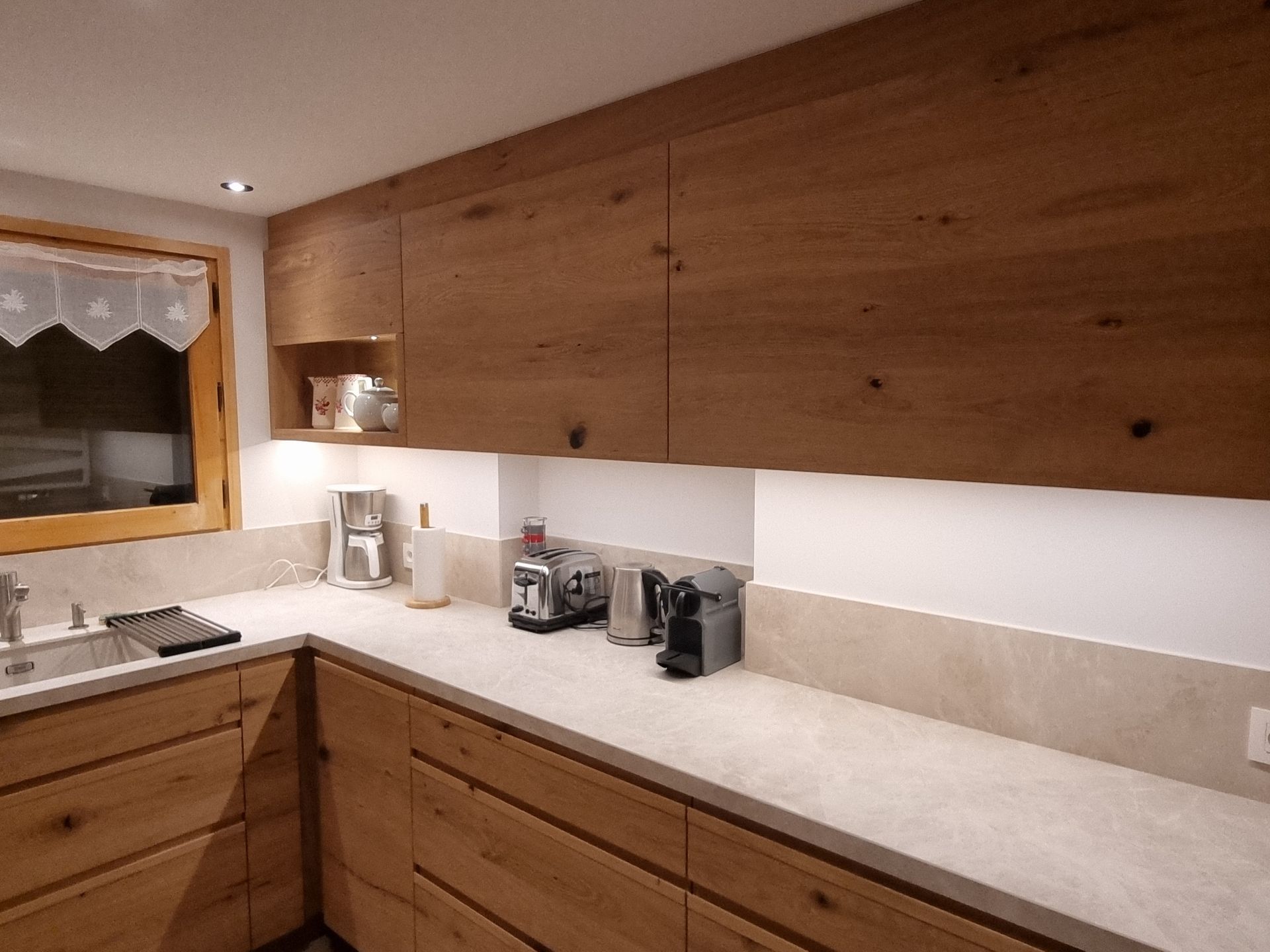 Cuisine équipée d'armoires en bois, de comptoirs clairs et d'électroménagers.