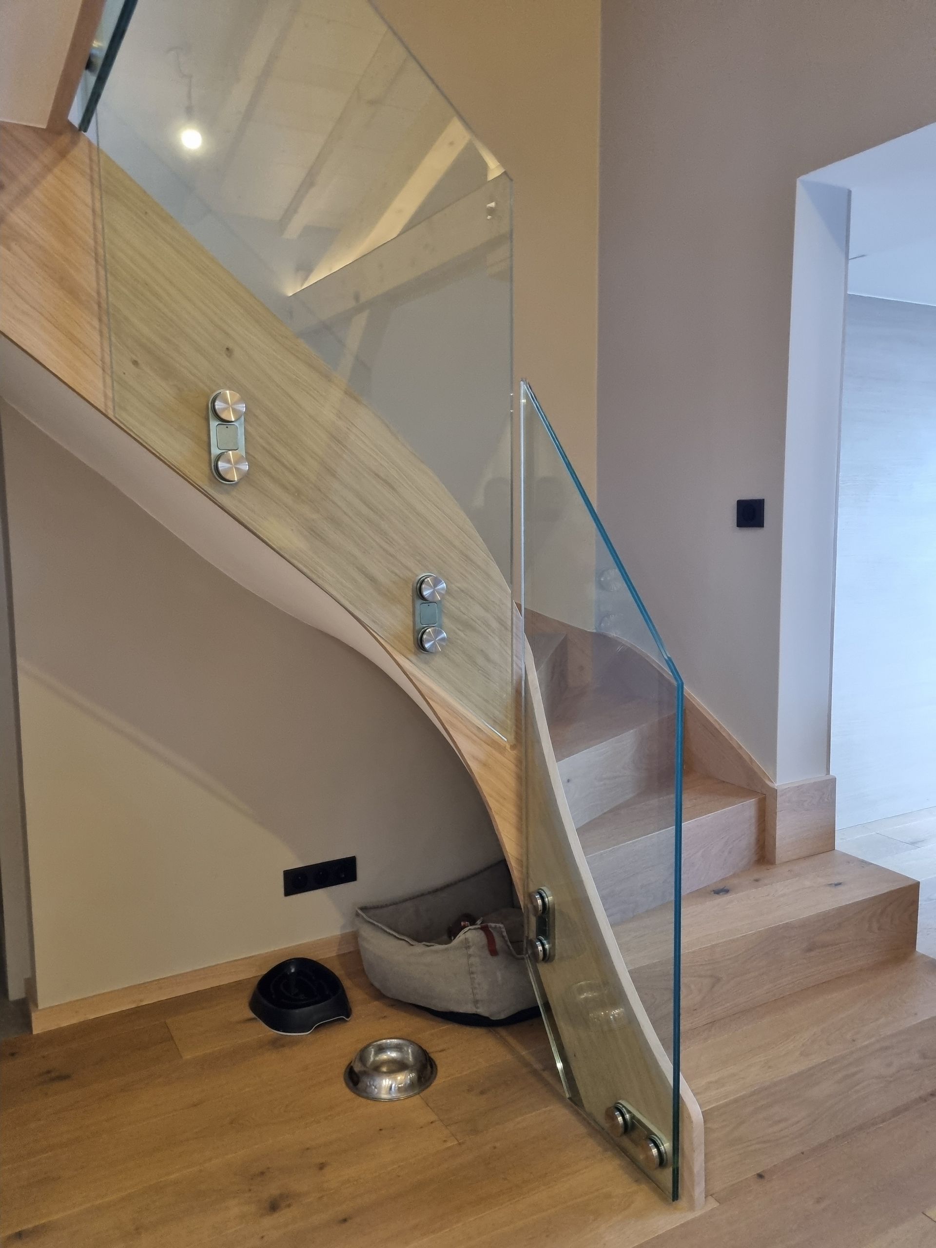 Escalier en bois avec rambarde en verre. Marches et rambarde en bois clair sur fond de murs beiges.