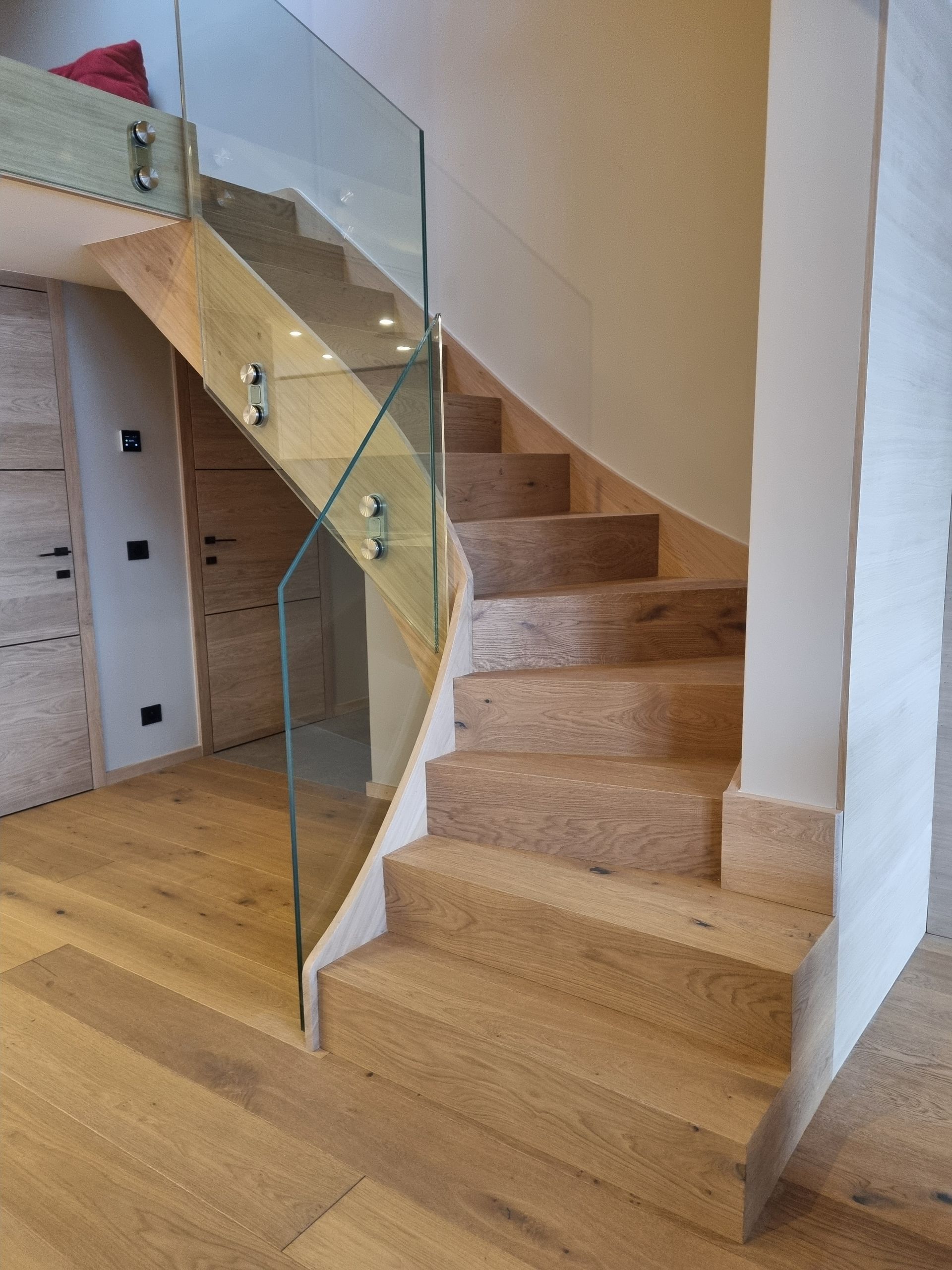 Escalier avec marches en bois et rambarde en verre dans une maison moderne.