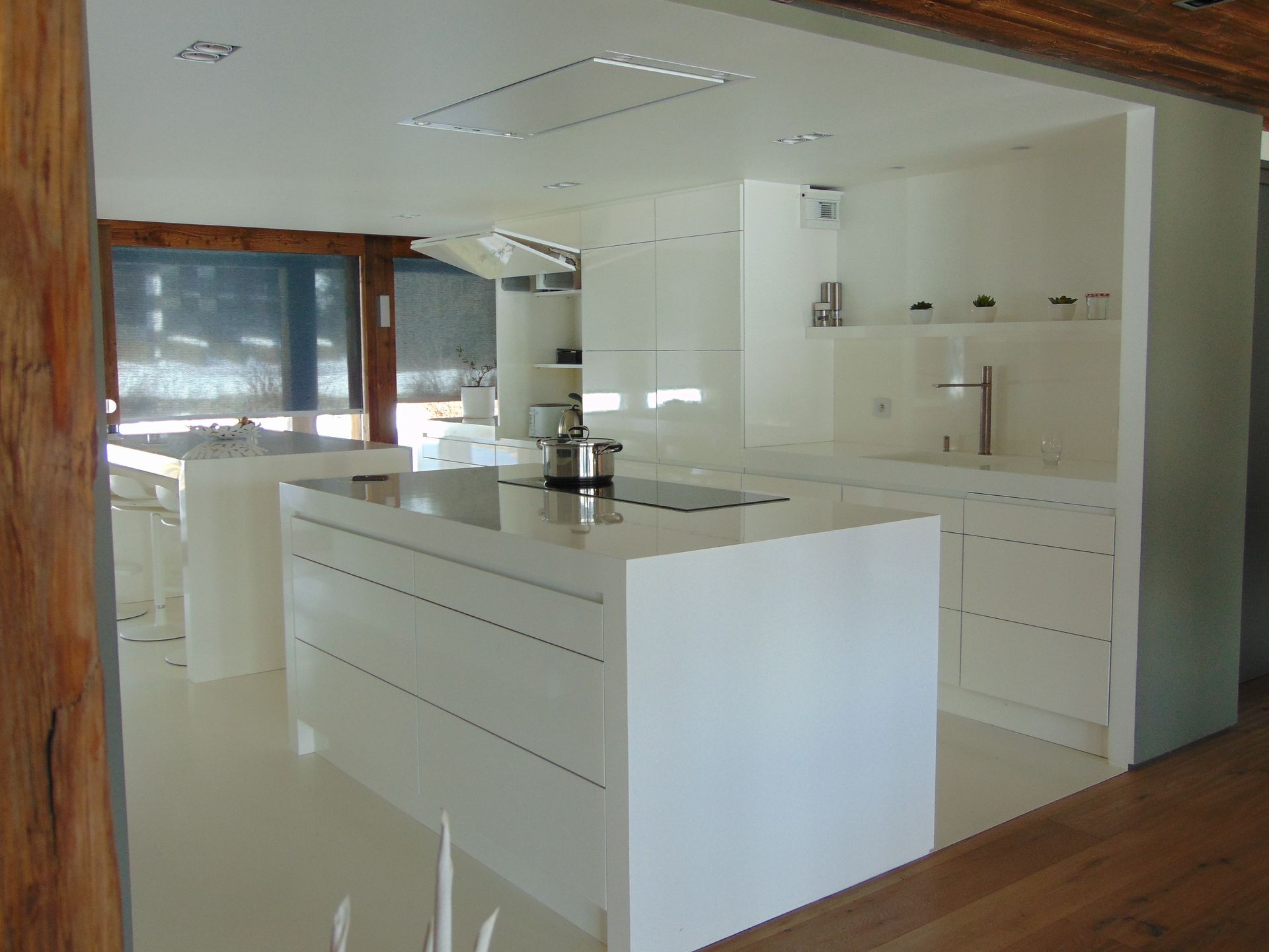 Cuisine blanche moderne avec îlot central, placards et électroménager. Espace lumineux et ouvert.