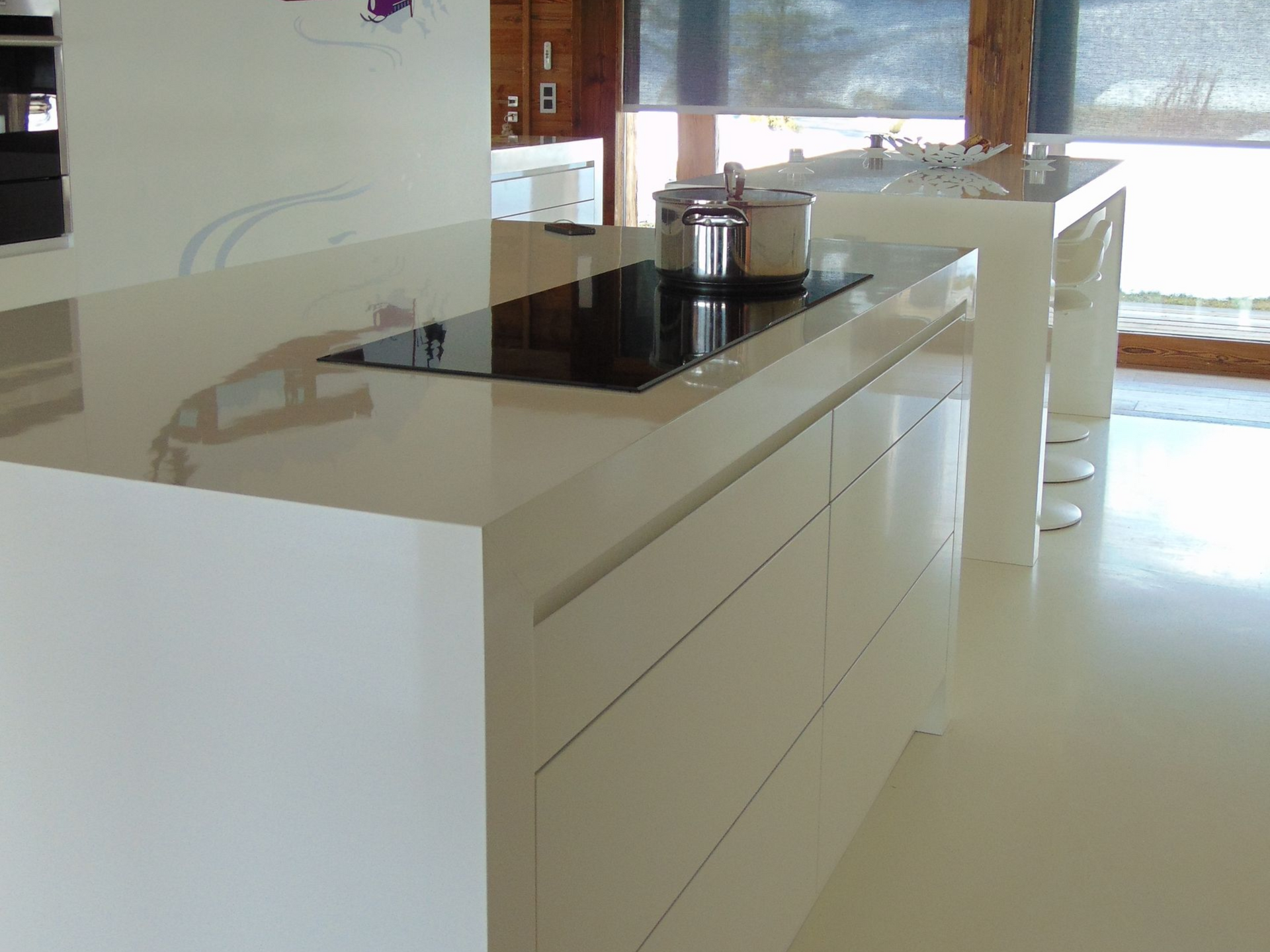 Îlot de cuisine blanc moderne avec plaque de cuisson, rangements pour casseroles et tiroirs.