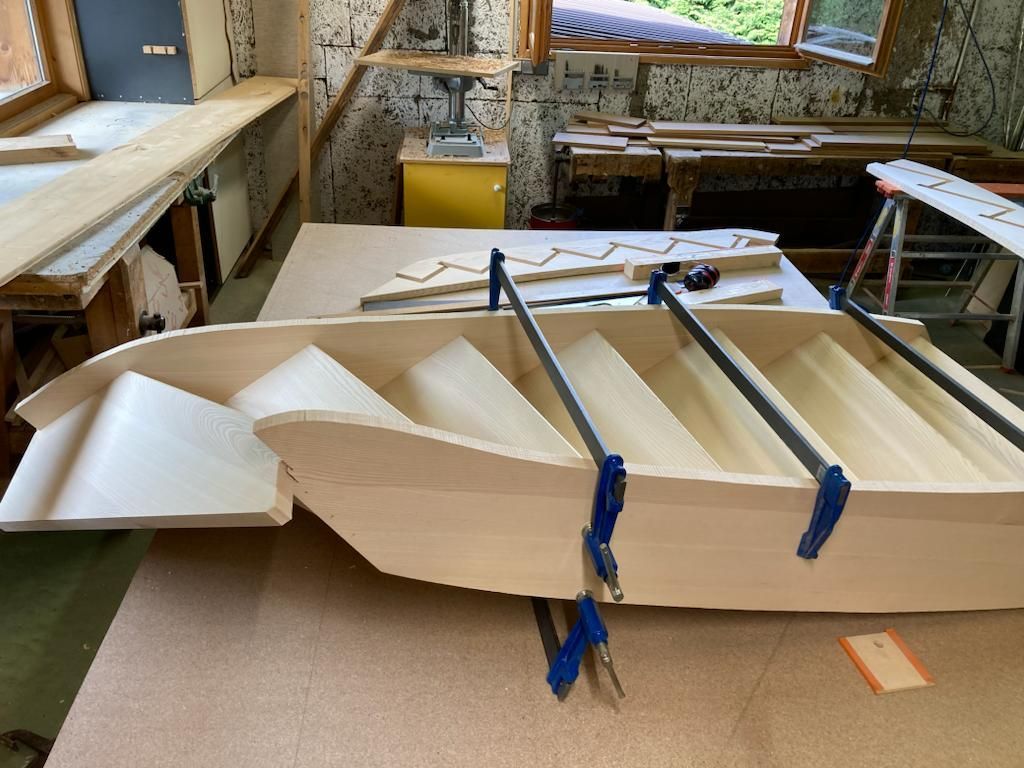 Construction d'un escalier en bois dans un atelier ; marches fixées aux supports latéraux.