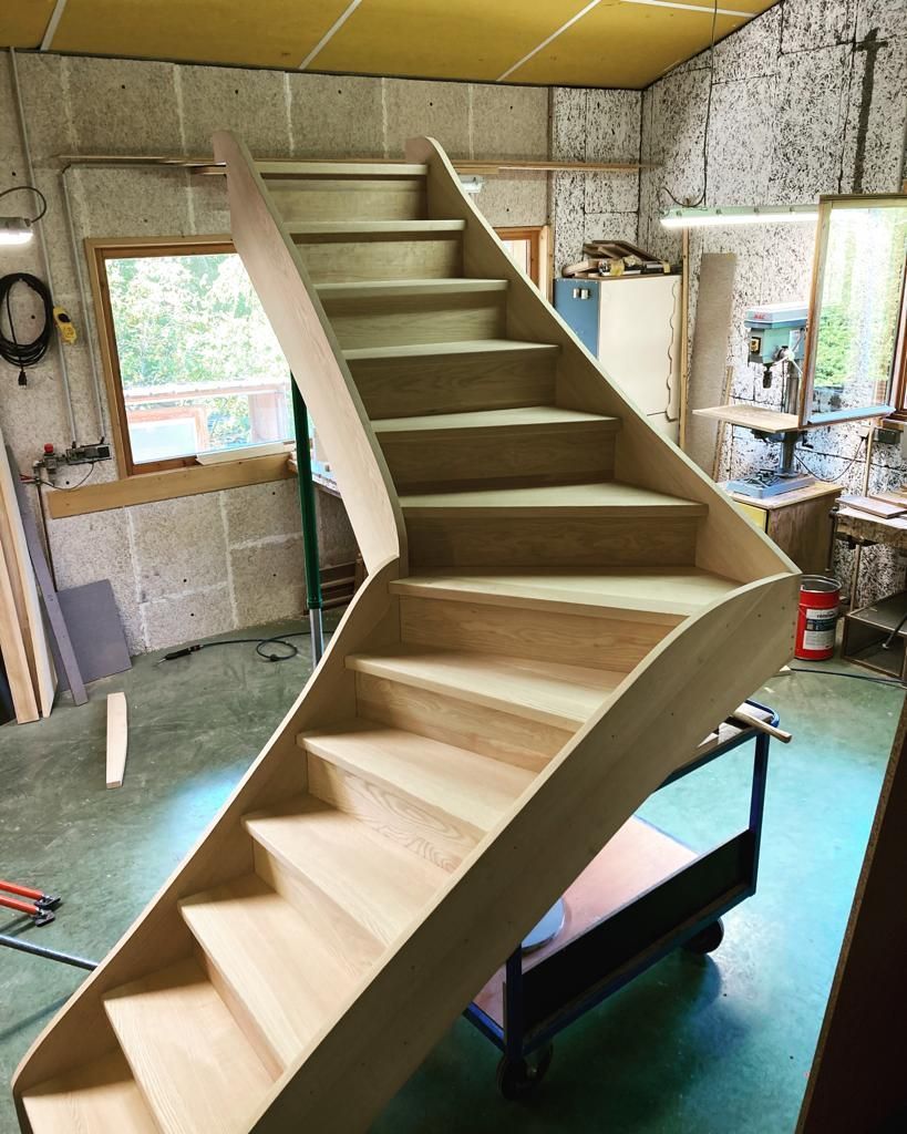 Escalier courbe en bois dans un atelier ; couleur bois naturel.