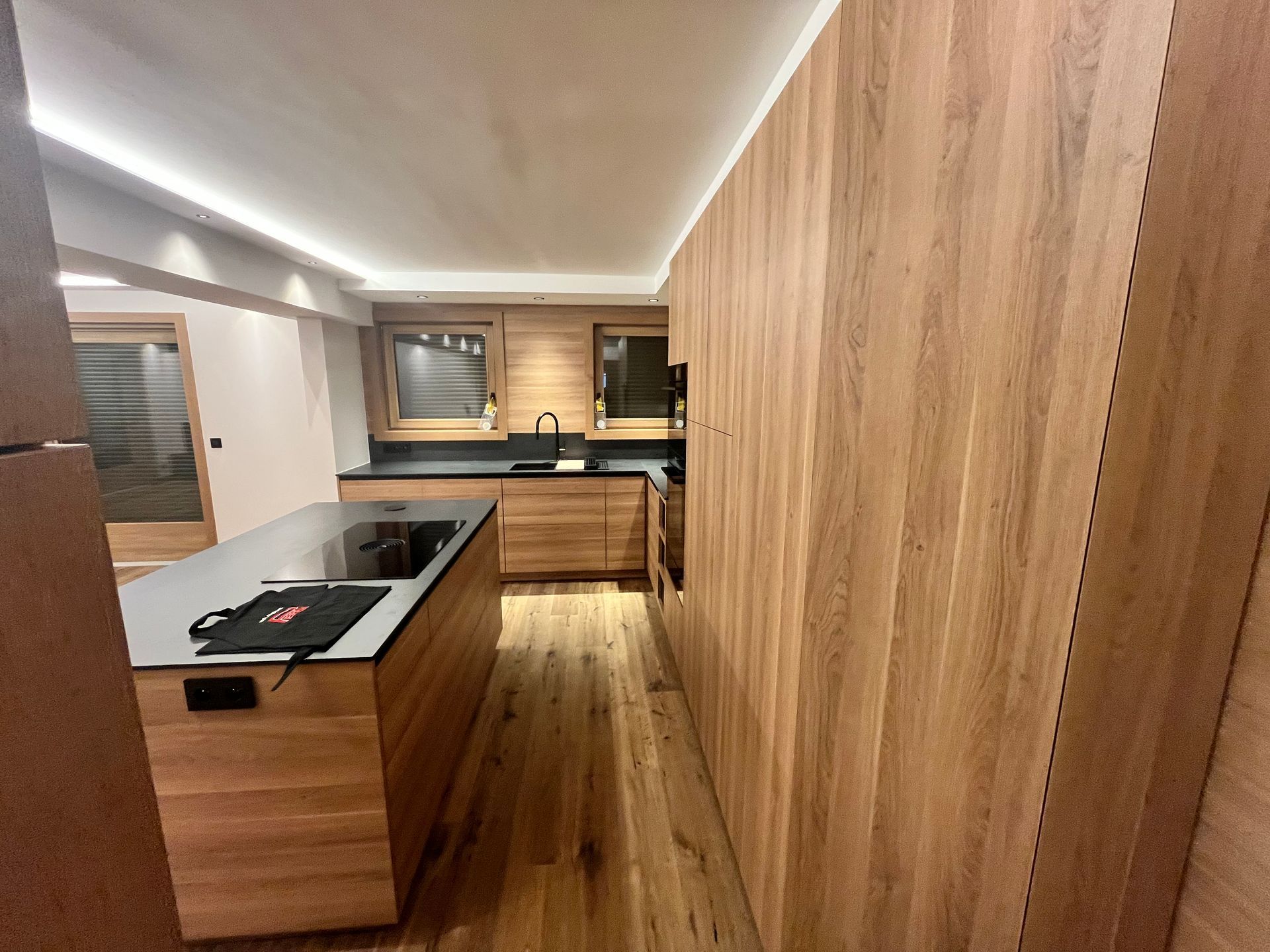 Cuisine moderne avec placards en bois, comptoirs noirs et îlot central.