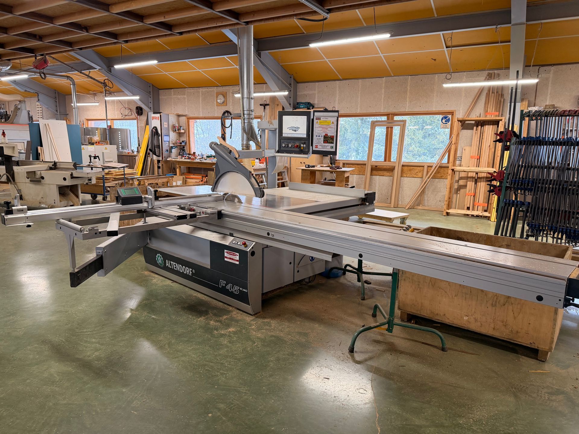 Grande scie à bois dans un atelier avec du bois et des outils.