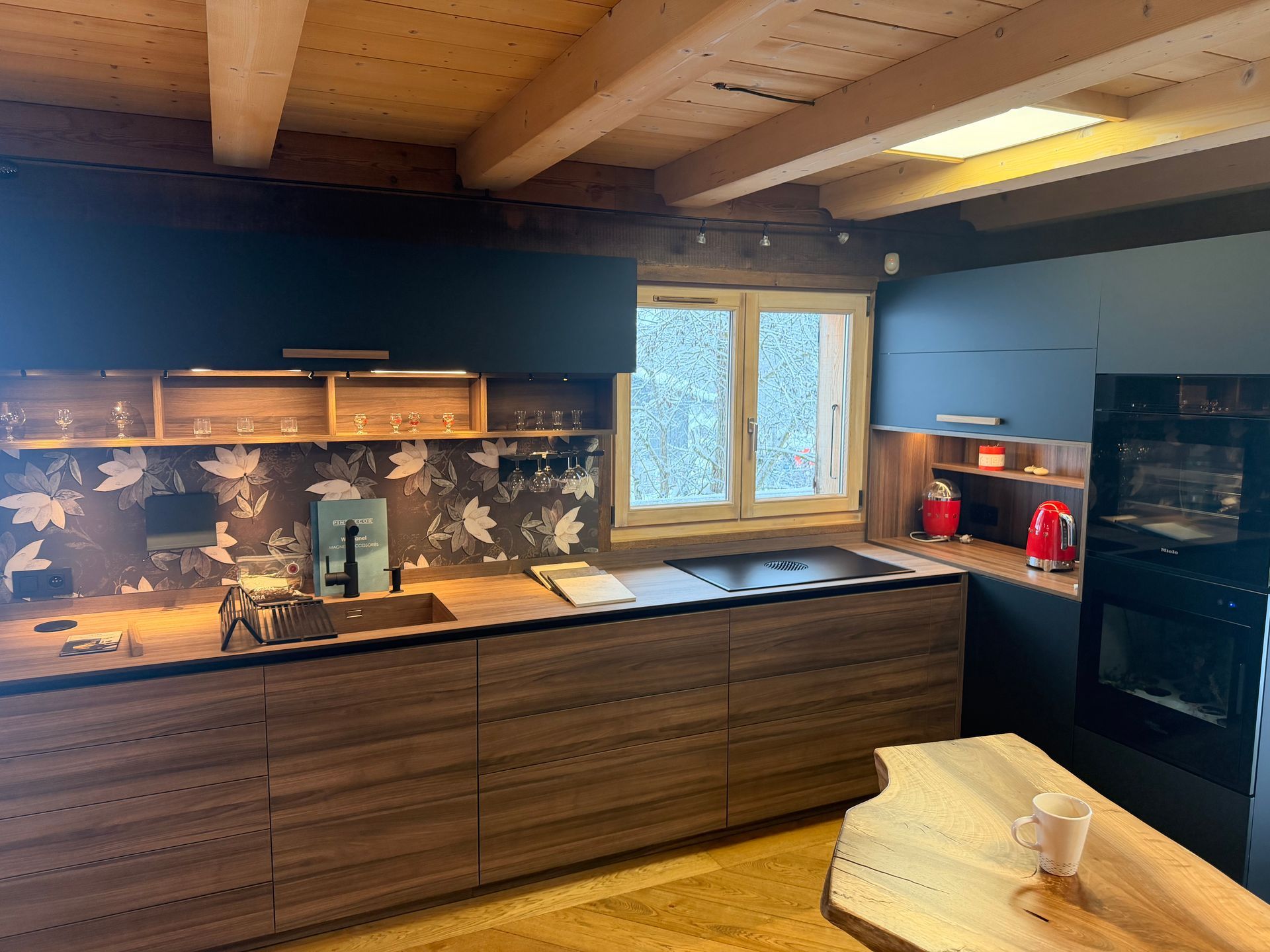 Cuisine moderne en bois avec placards noirs et bleus, appareils électroménagers en acier inoxydable et une fenêtre.