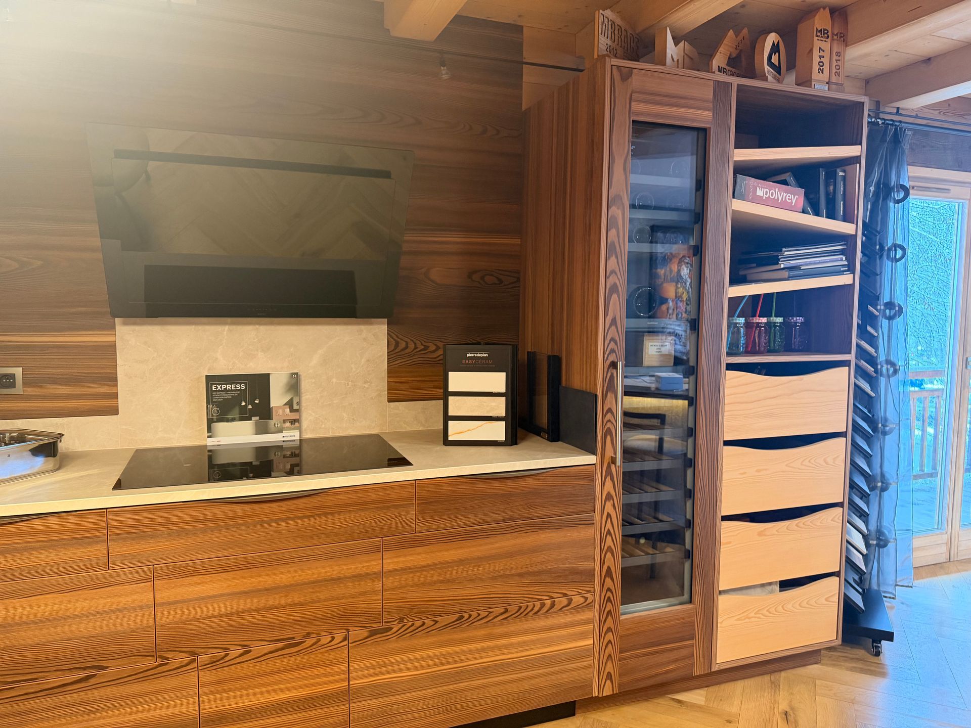 Cuisine en bois avec placards intégrés, appareils électroménagers et étagères ouvertes, à côté d'une porte vitrée.