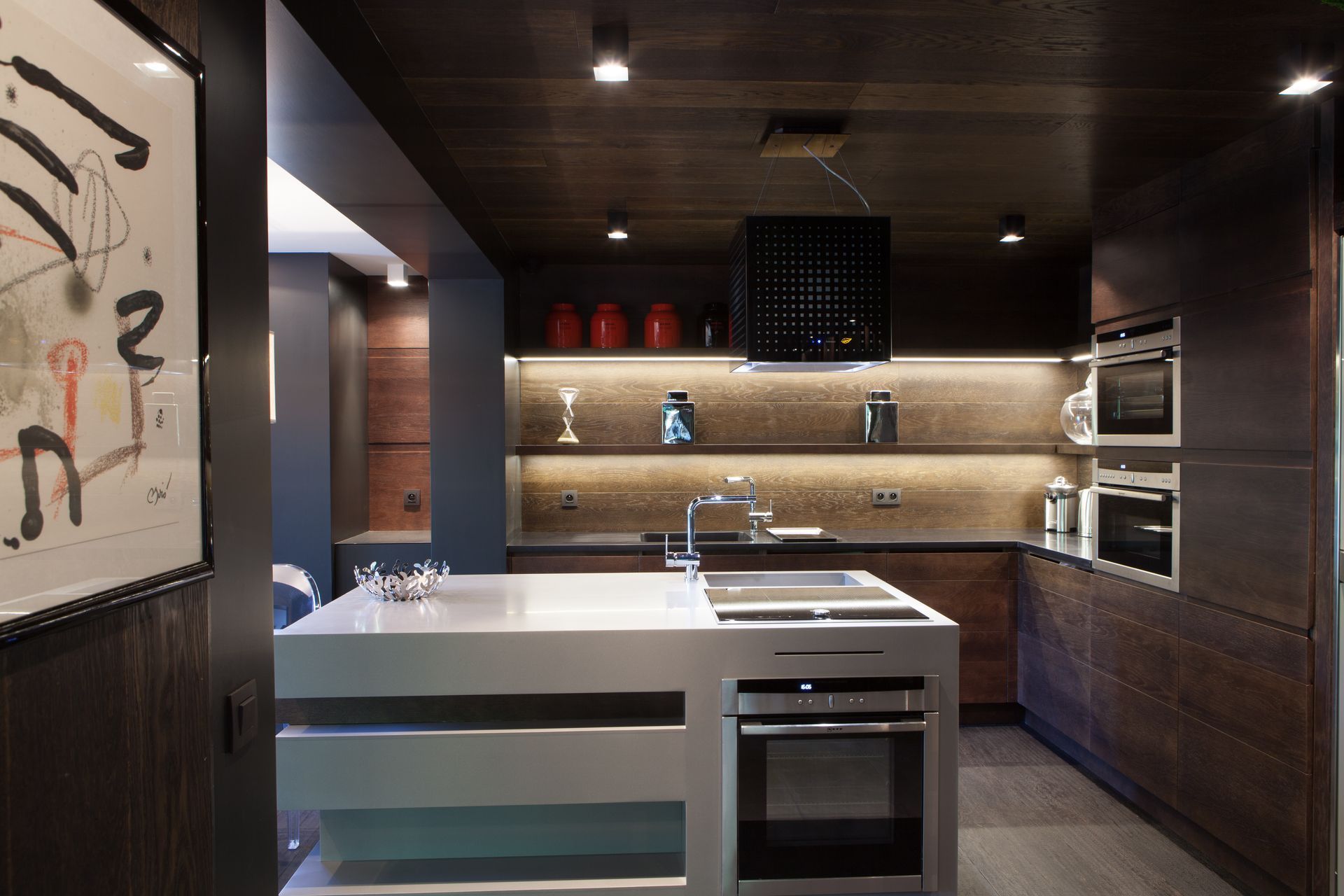 Cuisine moderne avec armoires en bois foncé, îlot central et électroménagers en acier inoxydable.