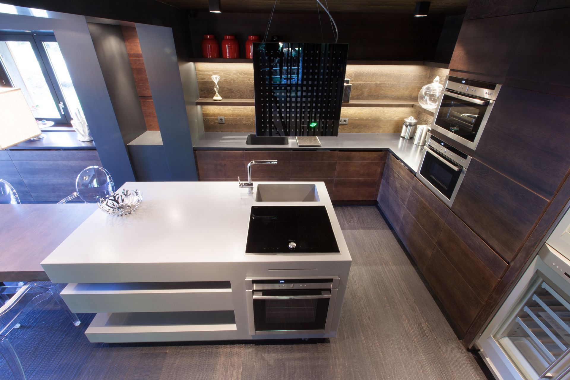 Cuisine moderne avec îlot central, appareils électroménagers intégrés, armoires en bois foncé et comptoirs clairs.