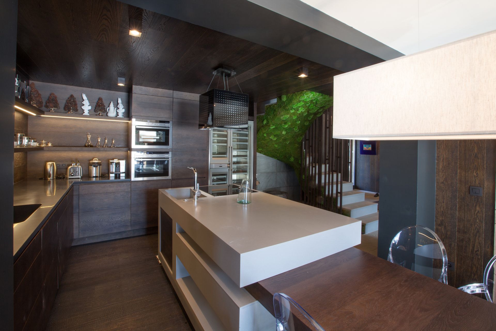 Cuisine moderne avec des armoires en bois foncé, un îlot central clair et un mur vert.