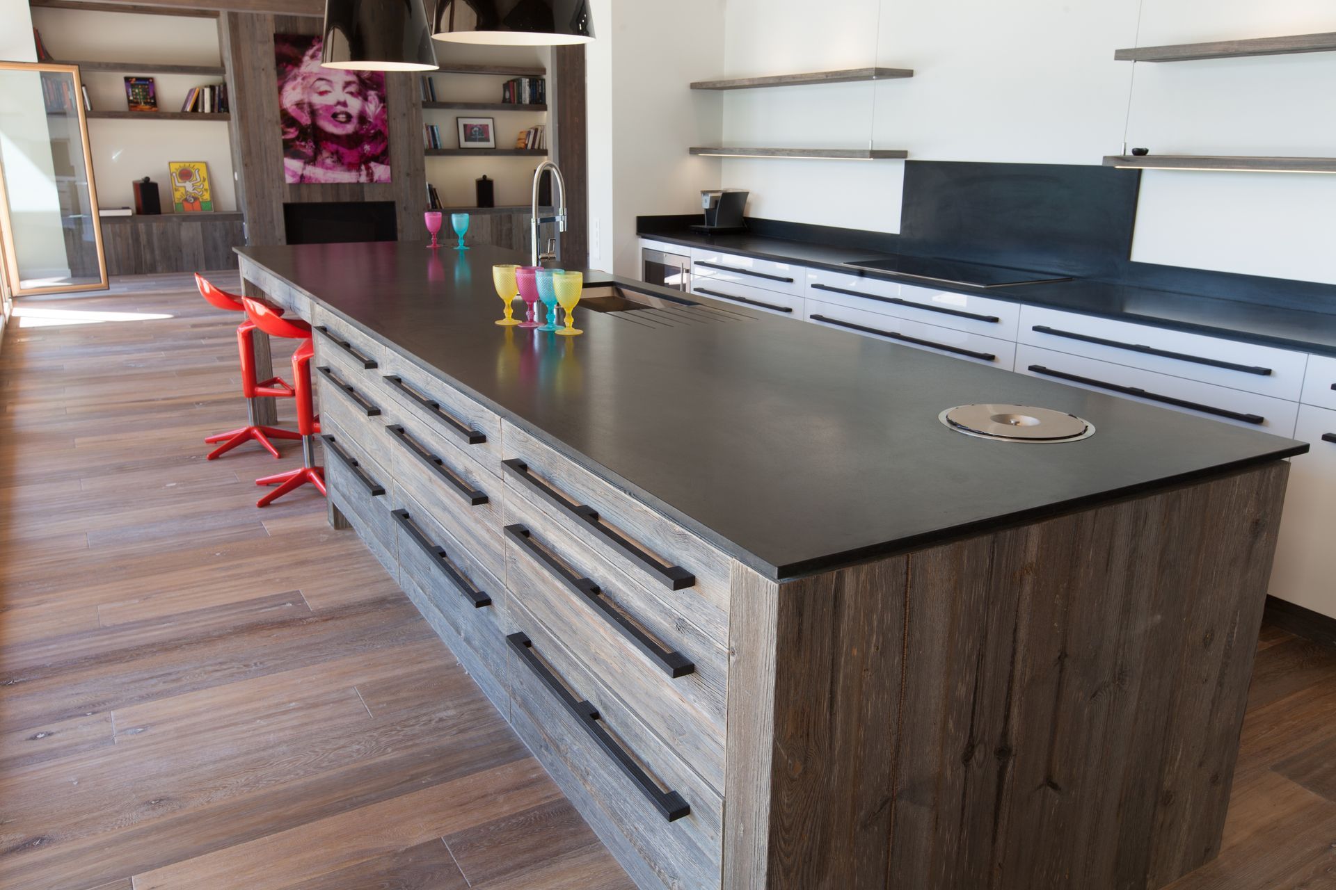 Îlot de cuisine avec comptoir gris, armoires en bois, tabourets de bar rouges.