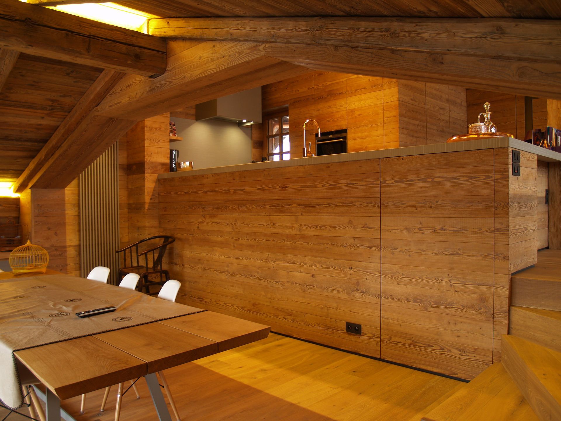 Cuisine et salle à manger en bois de style rustique, avec un comptoir intégré et des poutres apparentes.