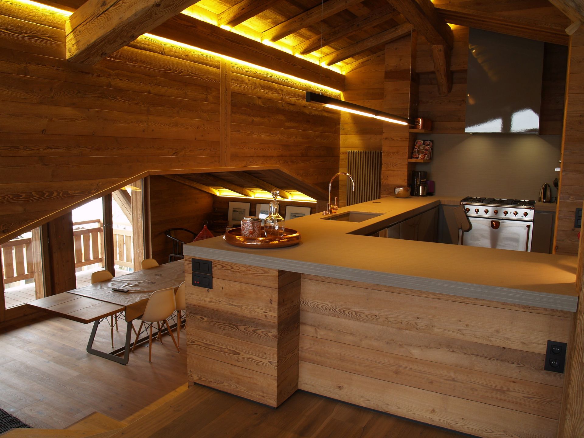 Cuisine rustique avec lambris, plan de travail clair et cuisinière à gaz.