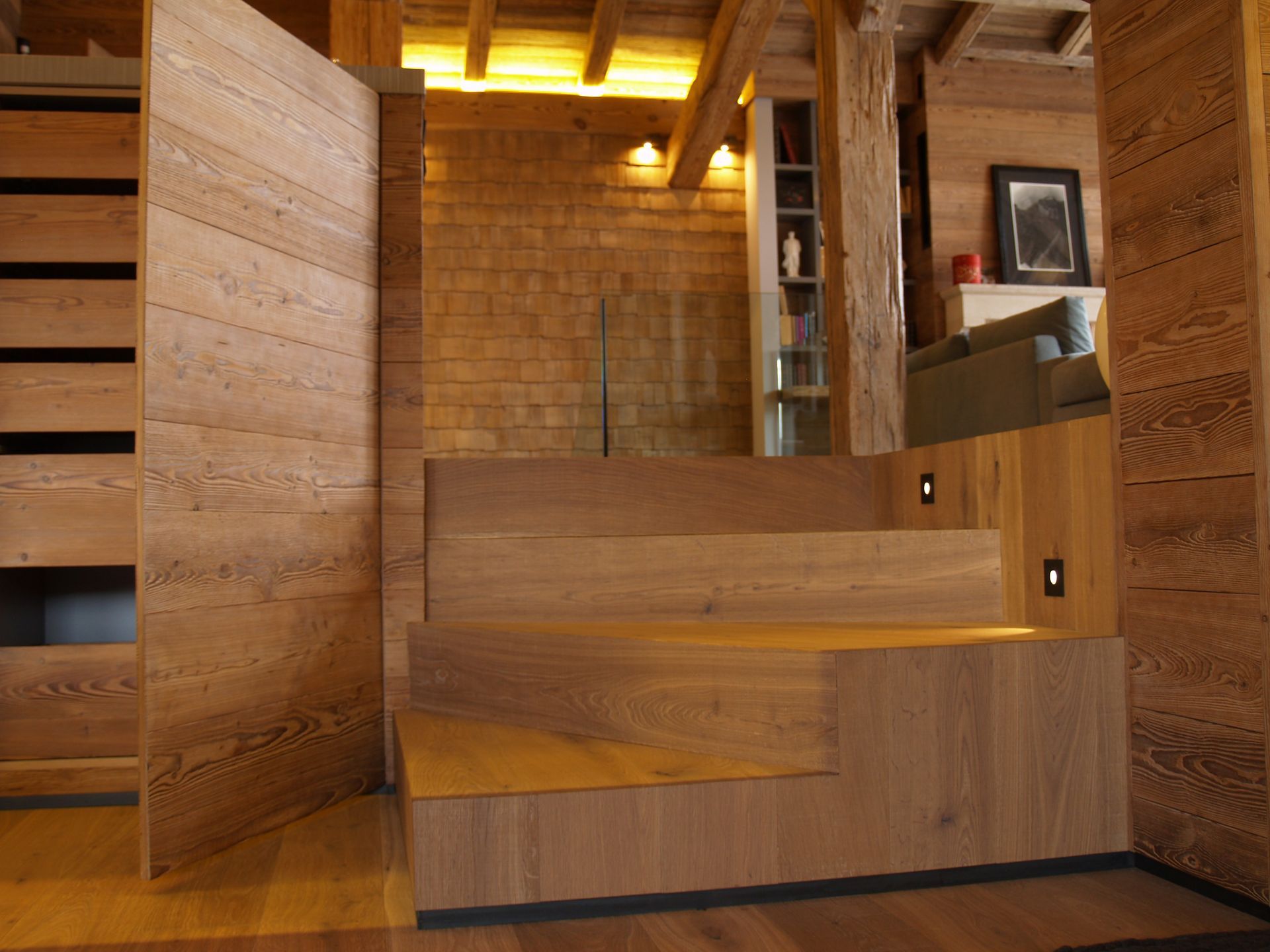 Escalier en bois dans un chalet aux murs lambrissés et offrant une vue sur l'espace de vie.