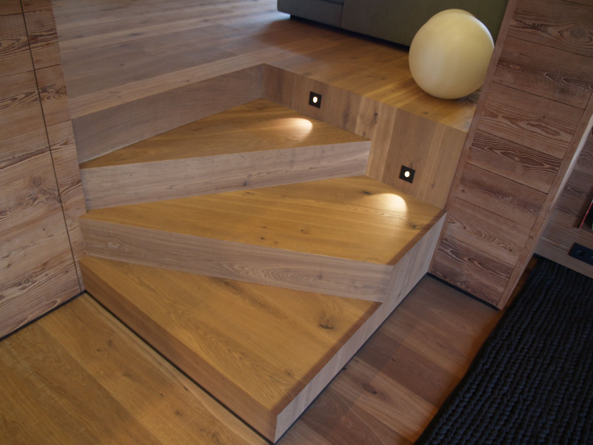 Escalier en bois avec éclairage intégré et sphère décorative.