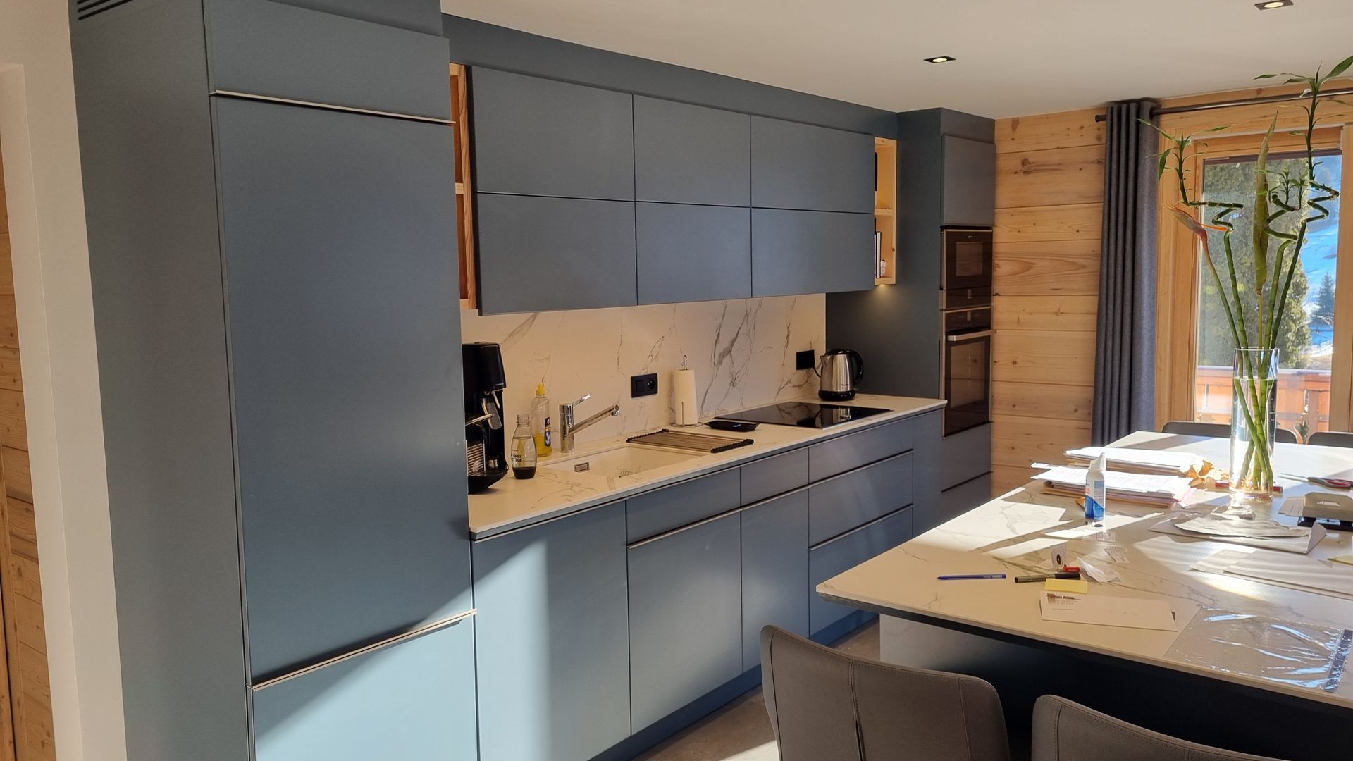 Cuisine moderne bleue avec comptoirs blancs et touches de bois.