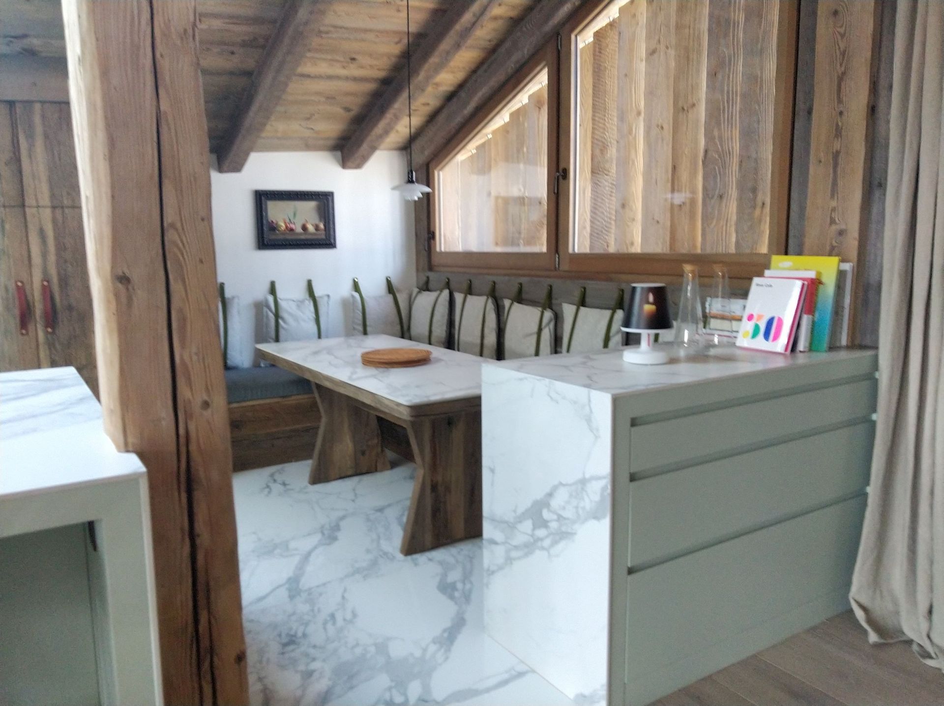 Coin cuisine avec comptoirs en marbre, table en bois et plafond en bois.