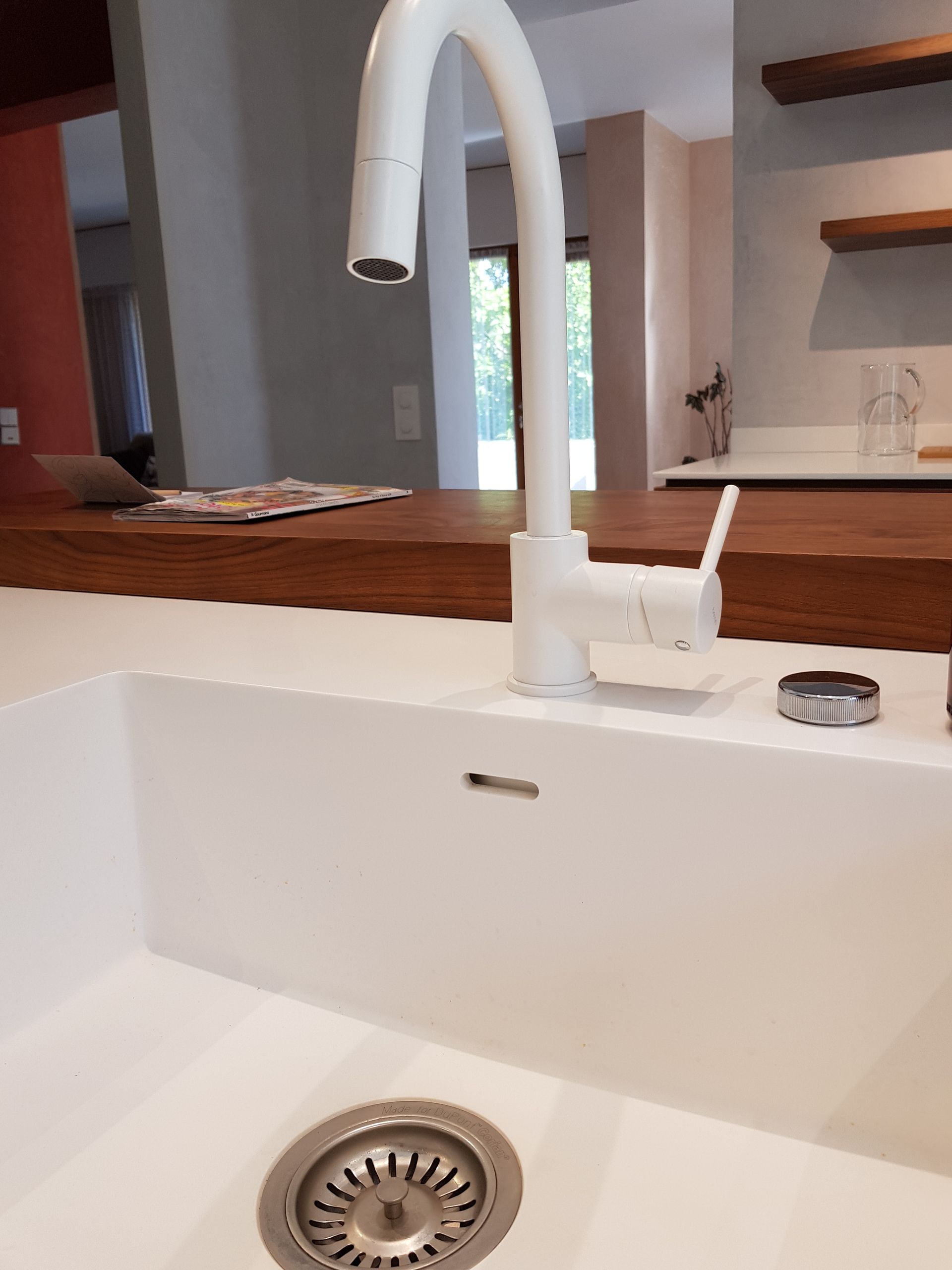 Robinet de cuisine blanc au-dessus d'un évier blanc avec un plan de travail en bois dans une cuisine moderne.