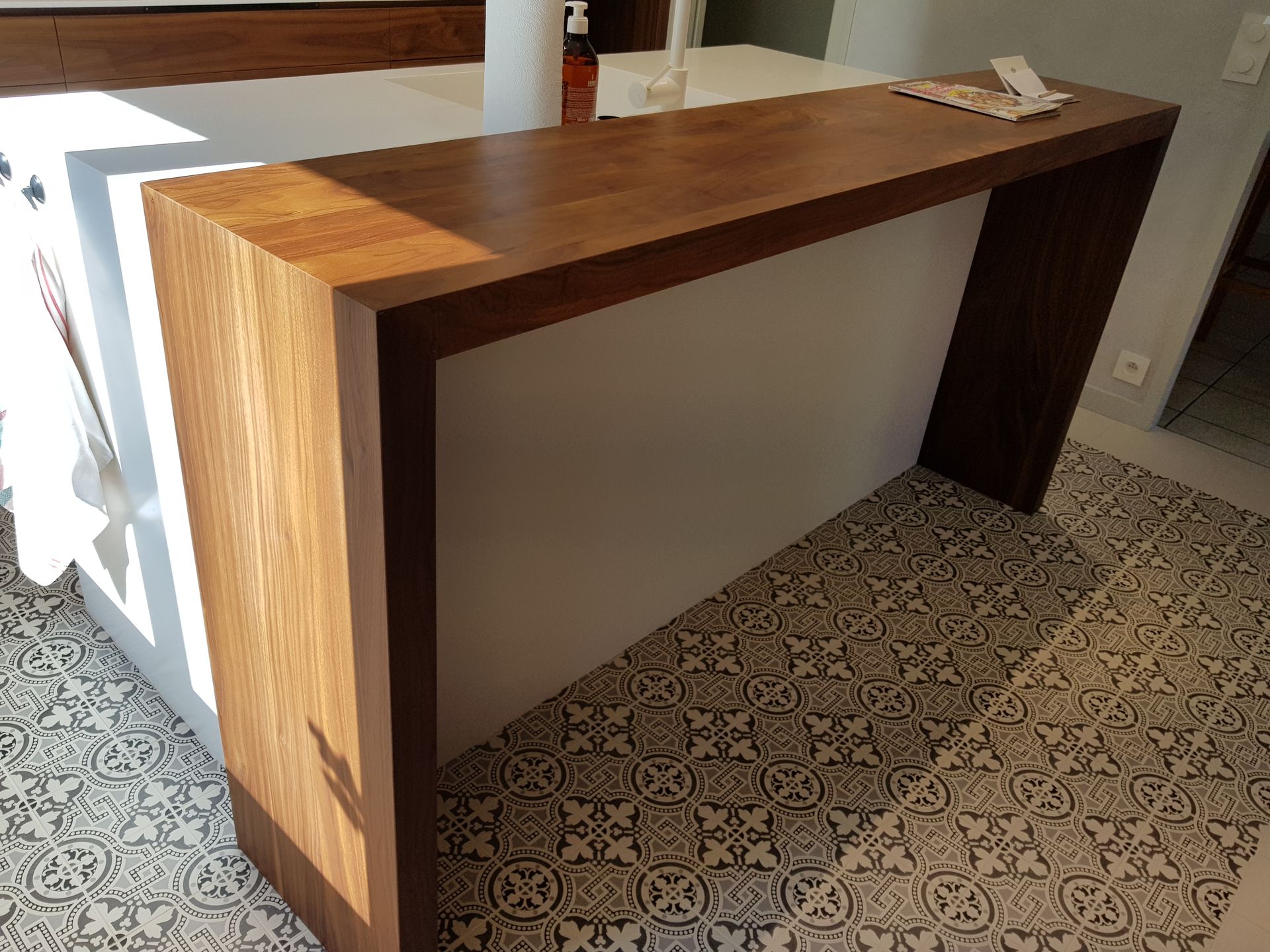 Plan de travail en bois dans le prolongement d'un îlot blanc. Sol carrelé.